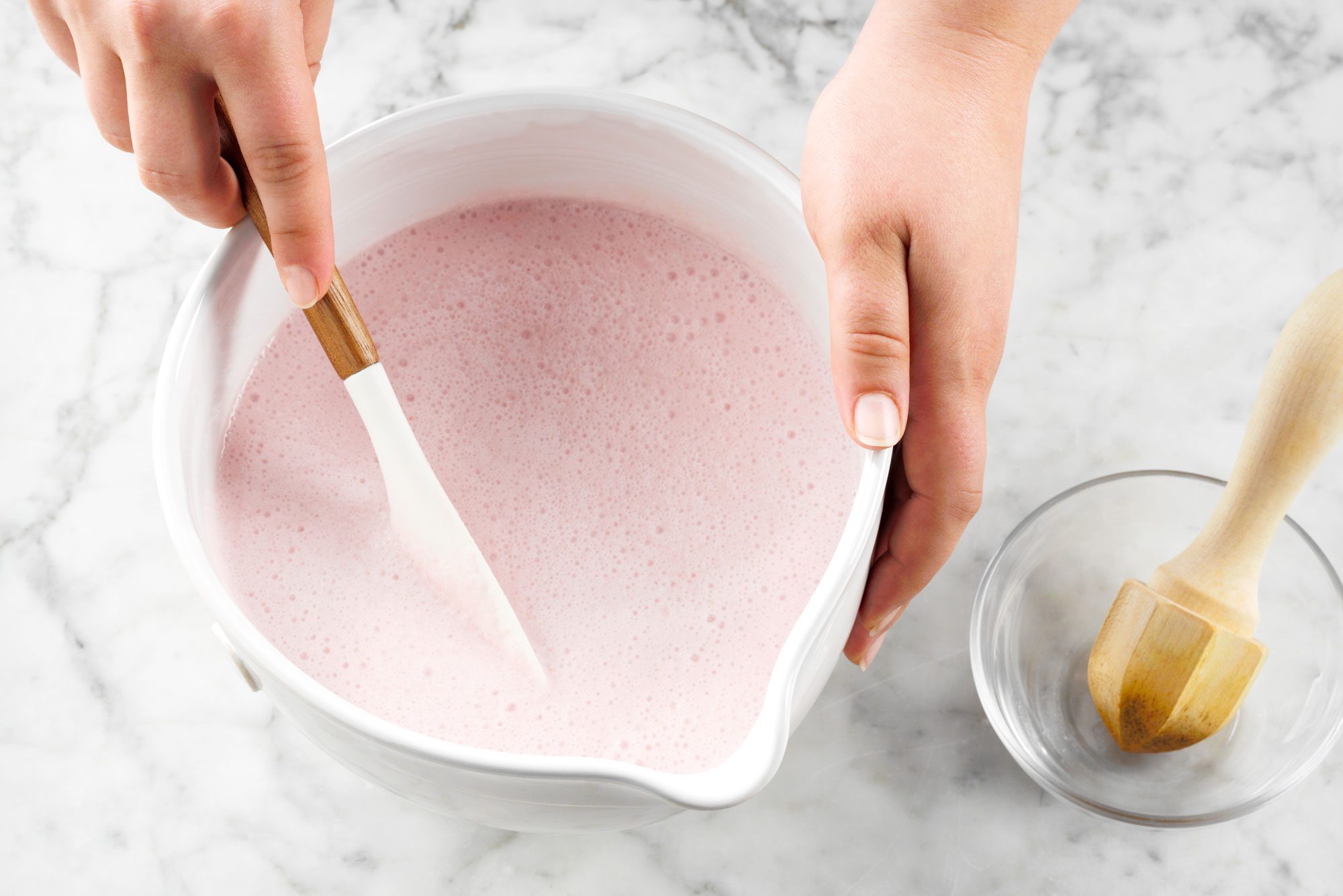 overhead shot of lemon juice added in the strawberry mixture in a bowl; marble surface;