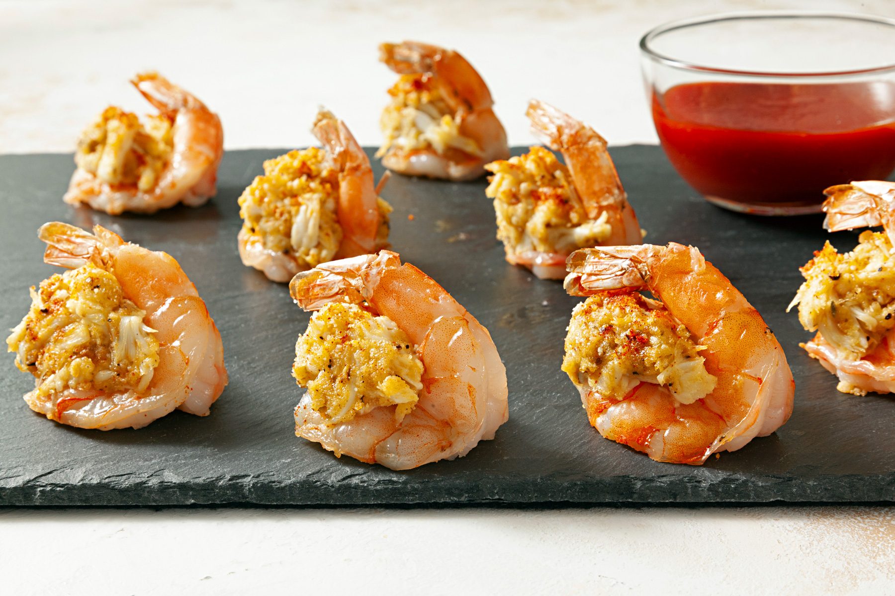 Stuffed Shrimp Appetizers on a black tray with a bowl of sauce