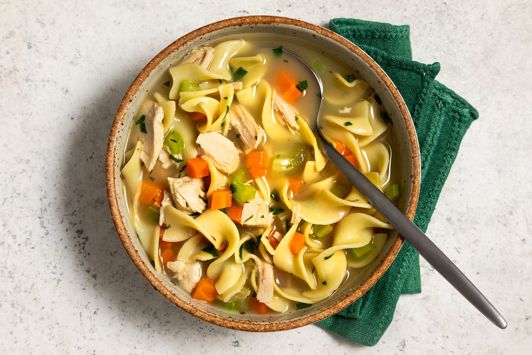 Turkey Noodle Soup served in a bowl with spoon and green tissue