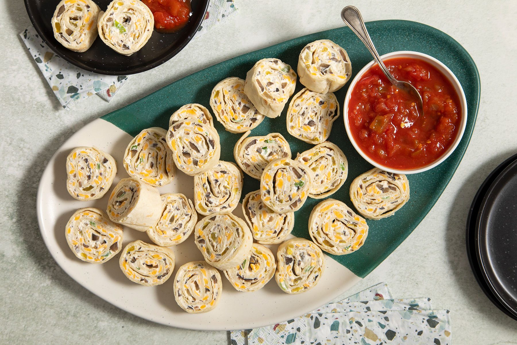 Appetizer Tortilla Pinwheels on plate with salsa dip in small bowl