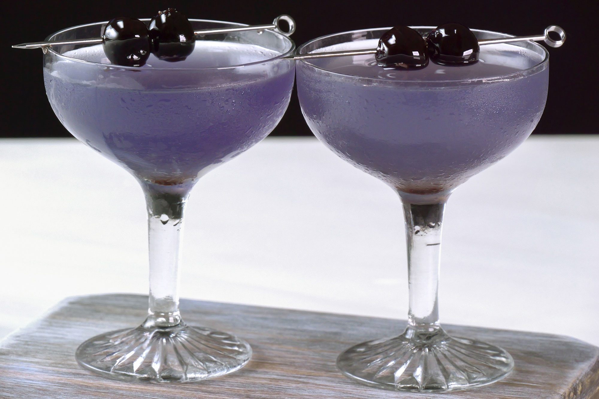 Aviation drink served in coupe glasses, Garnished with cherries