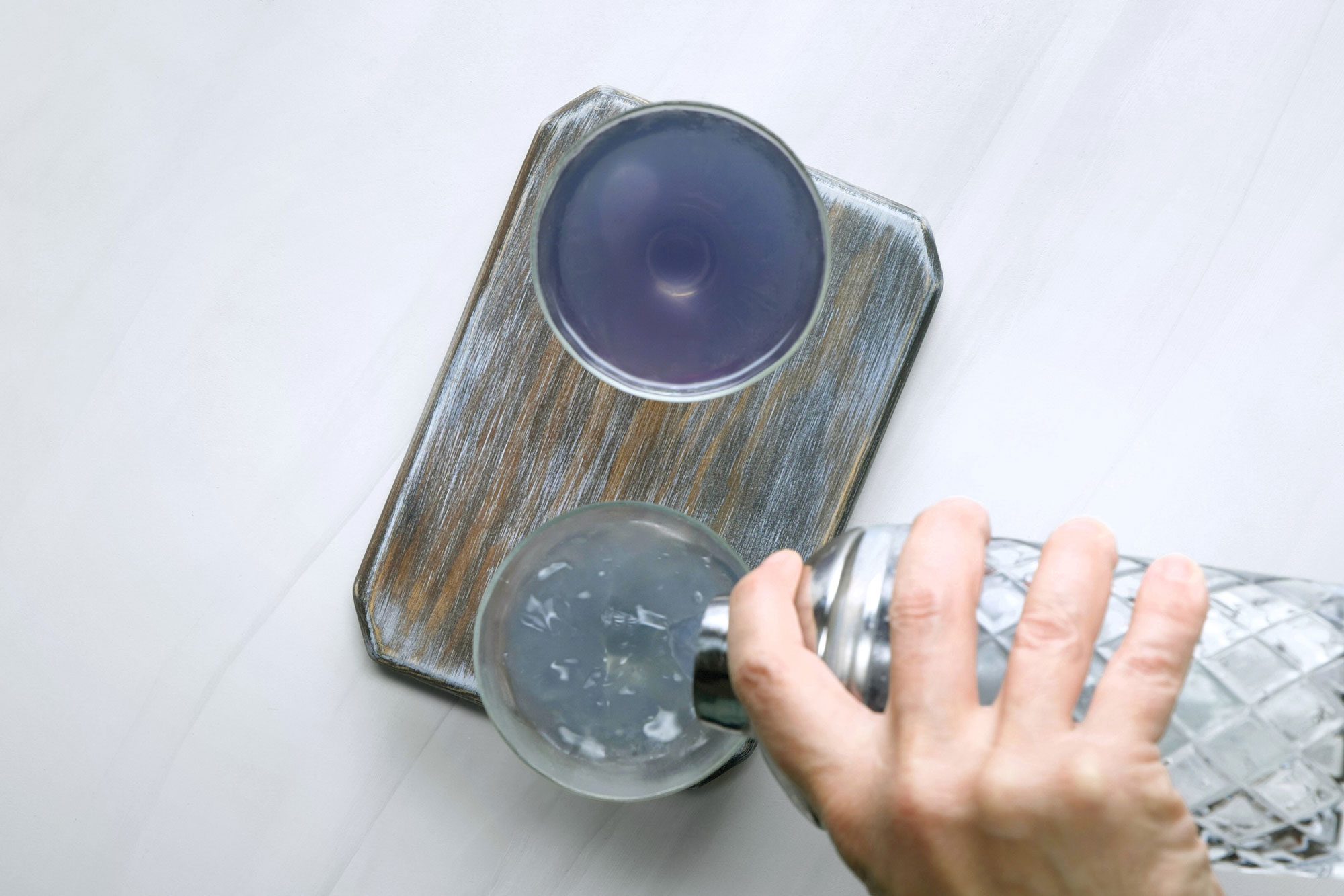 Pouring the drink into chilled coupe glasses from shaker