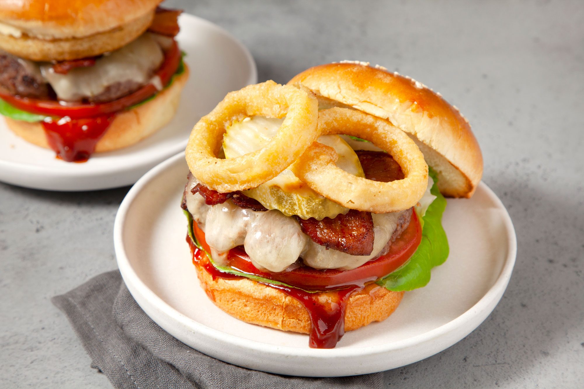 Two Delicious Barbecue Bacon Burger topped with onion rings and cheese