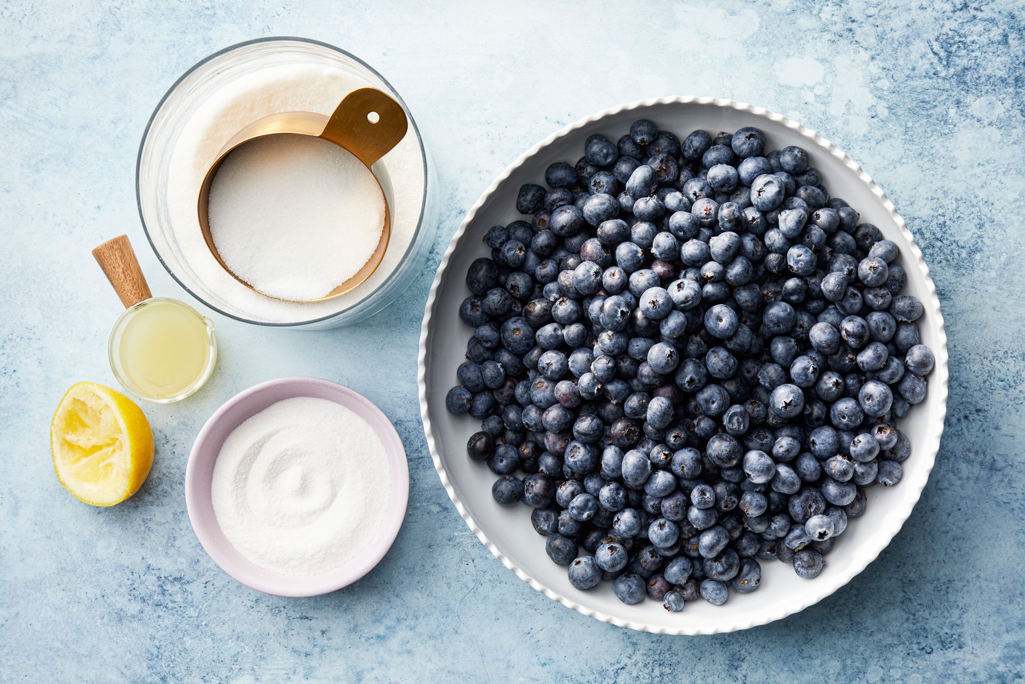 Overhead shot of blueberries and other ingredients for blueberry jam; blue texture background;