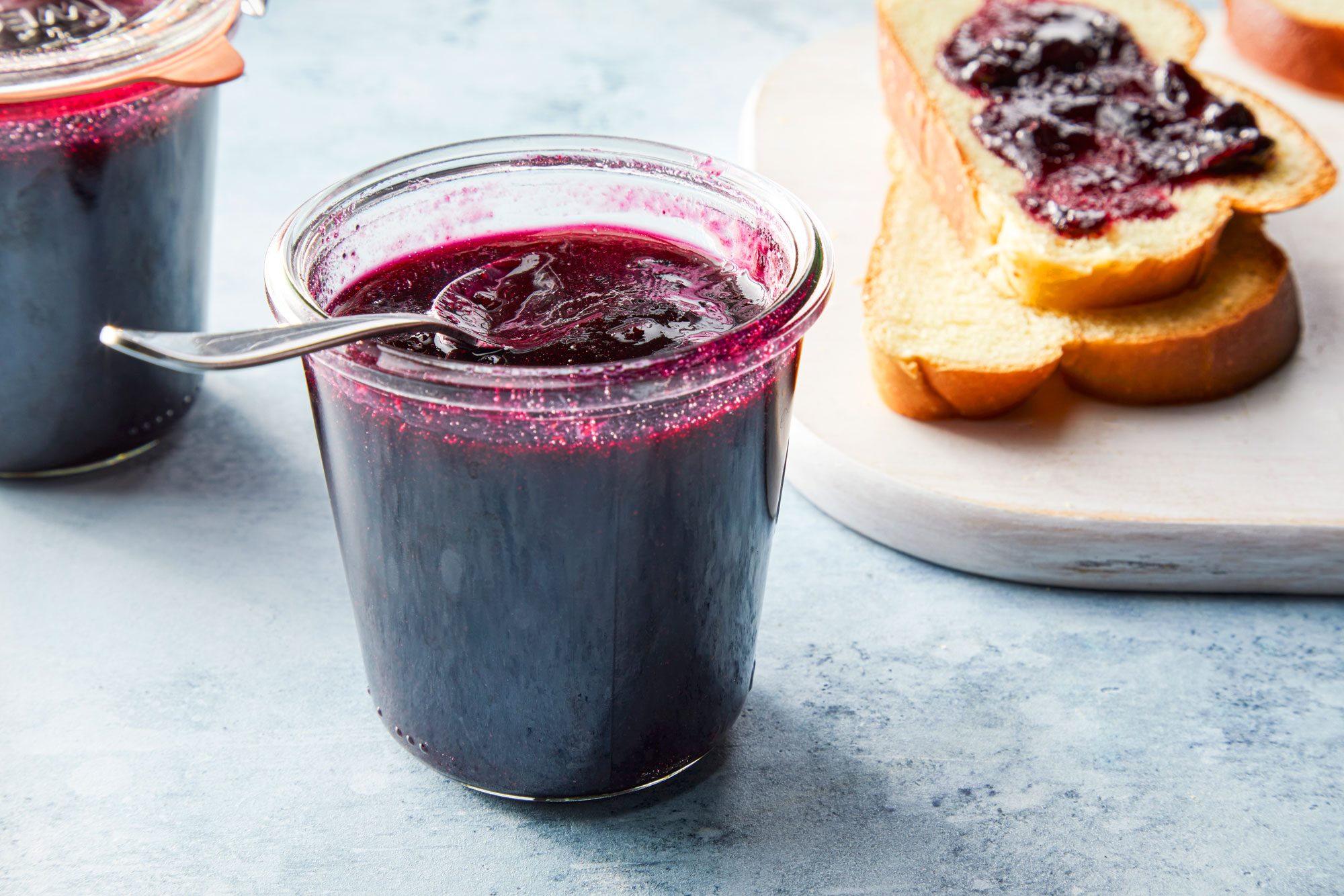 3/4 angle view shot of Luscious Blueberry Jam; spread on breads; store in glass jars; blue texture background;