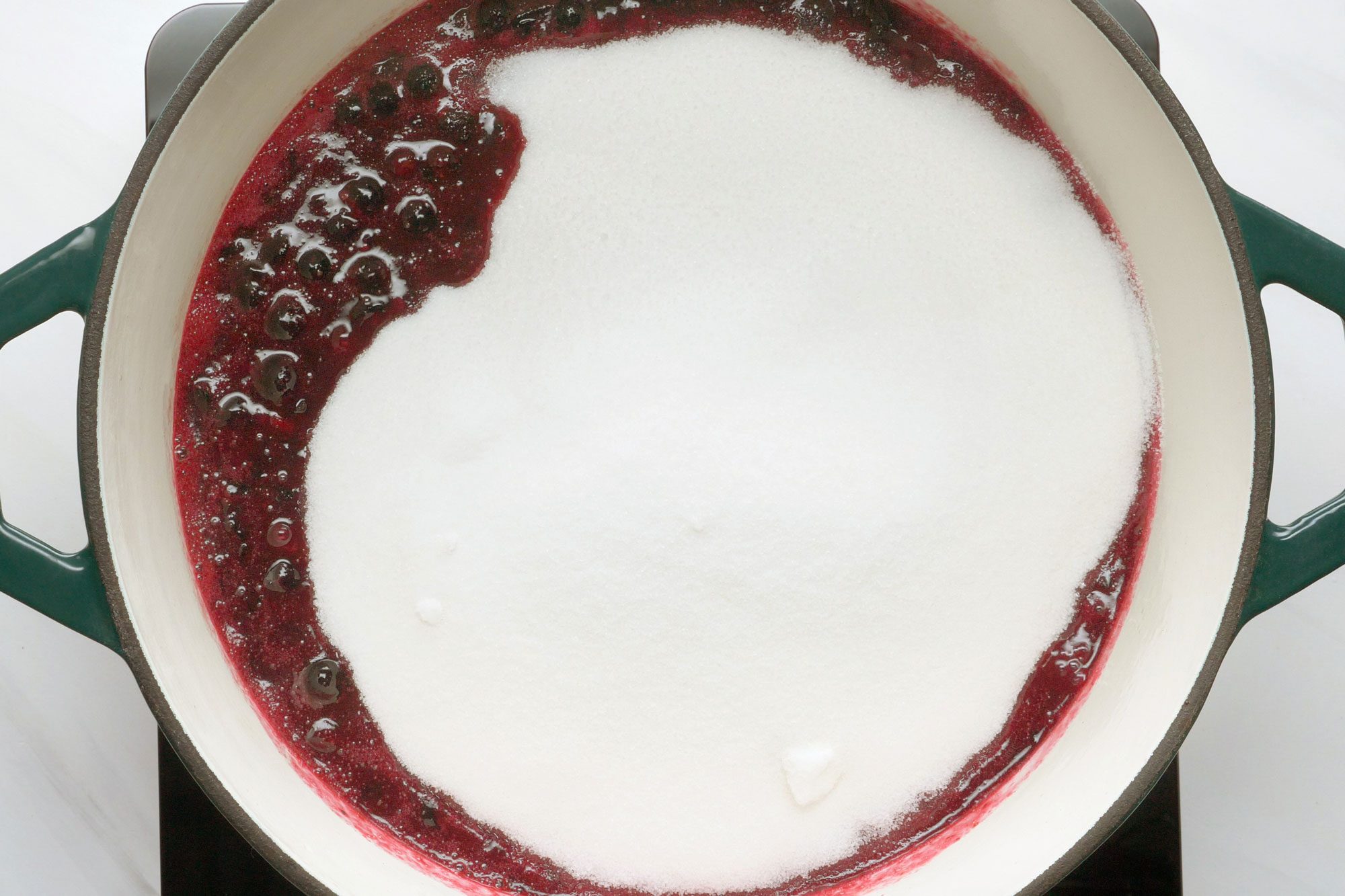 overhead shot of pectan added in the boiling blueberries in a dutch oven