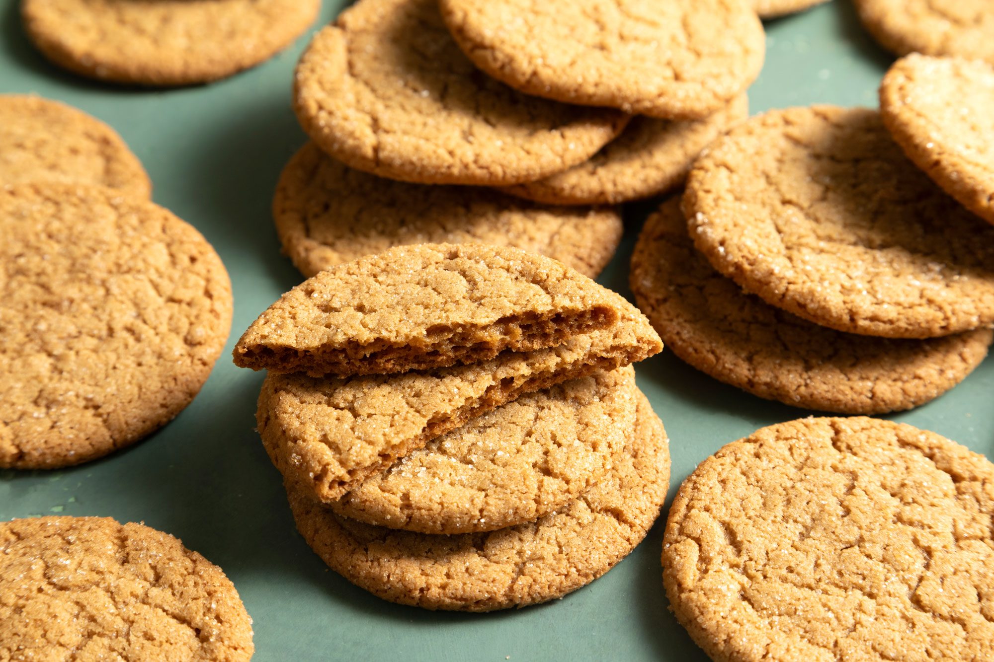 Crispy Brown Sugar Cookies stacked on each other on green background