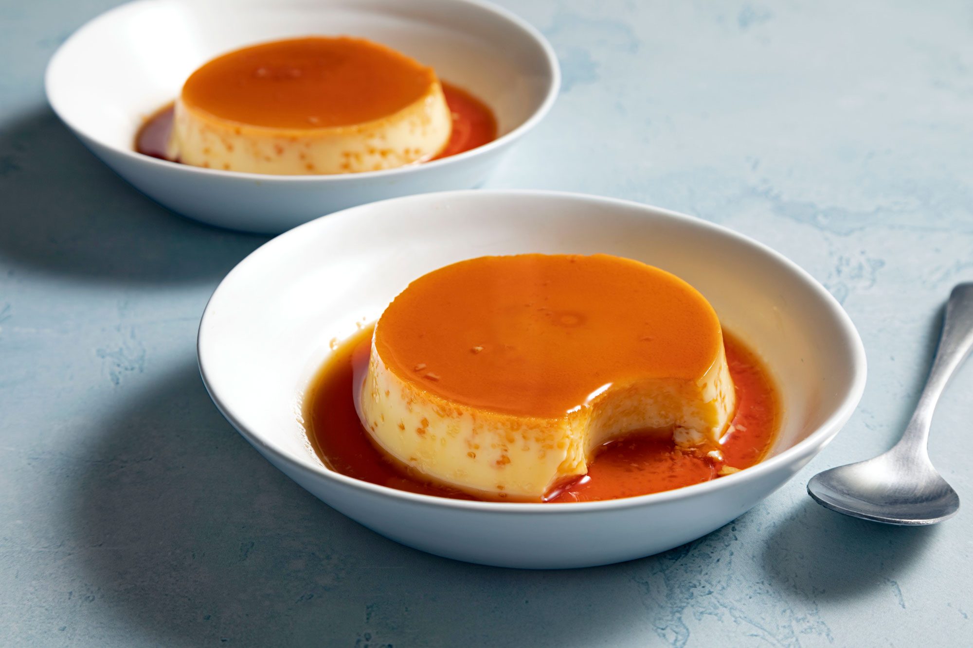 Two bowls of caramel custard with sauce