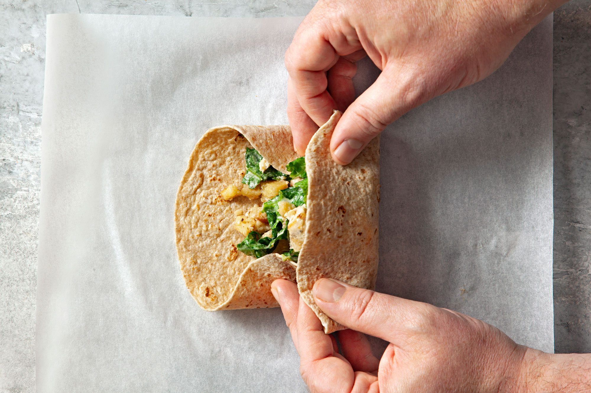 overhead shot of tortilla rolled up with hands