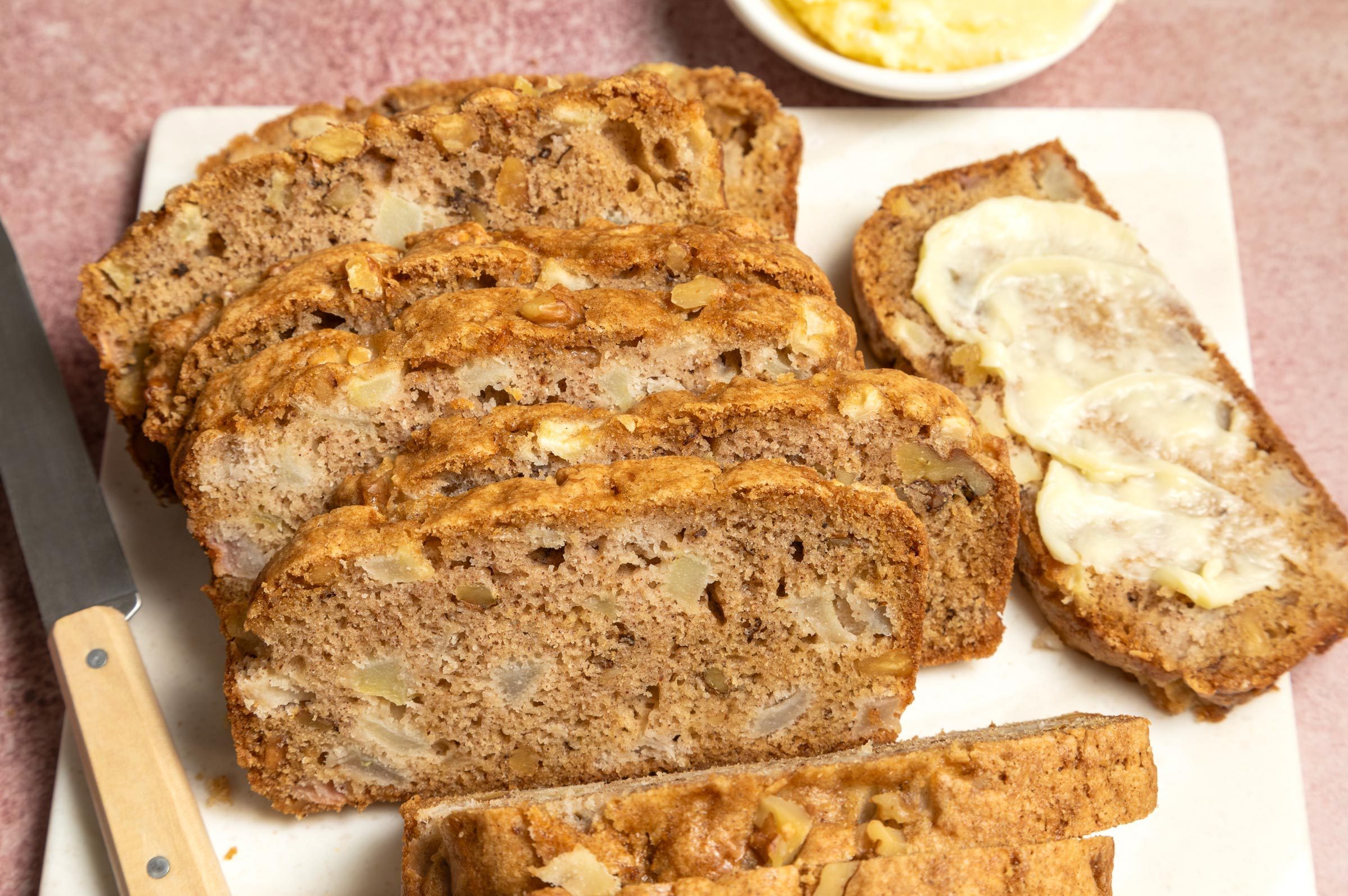 fresh Pear Bread on a cutting board cut into slices with a side of butter