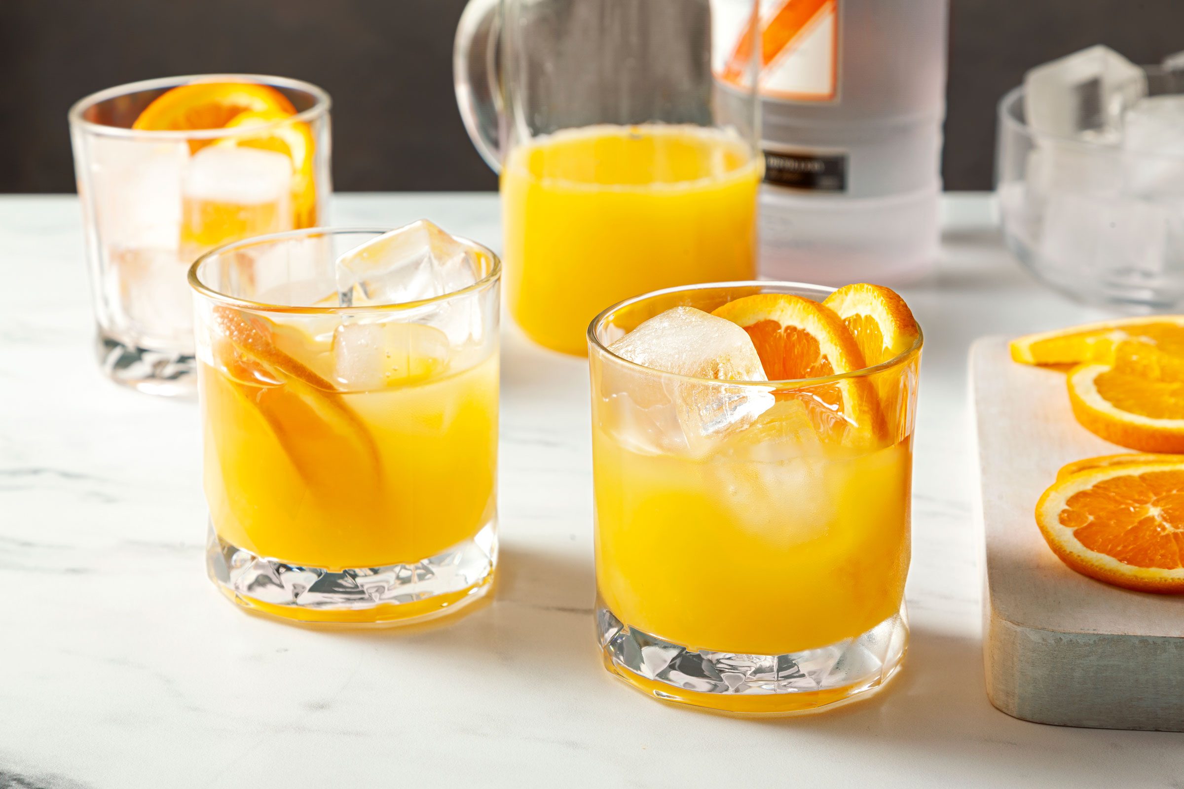 Two Screwdriver cocktails in glasses with the ingredients in the background