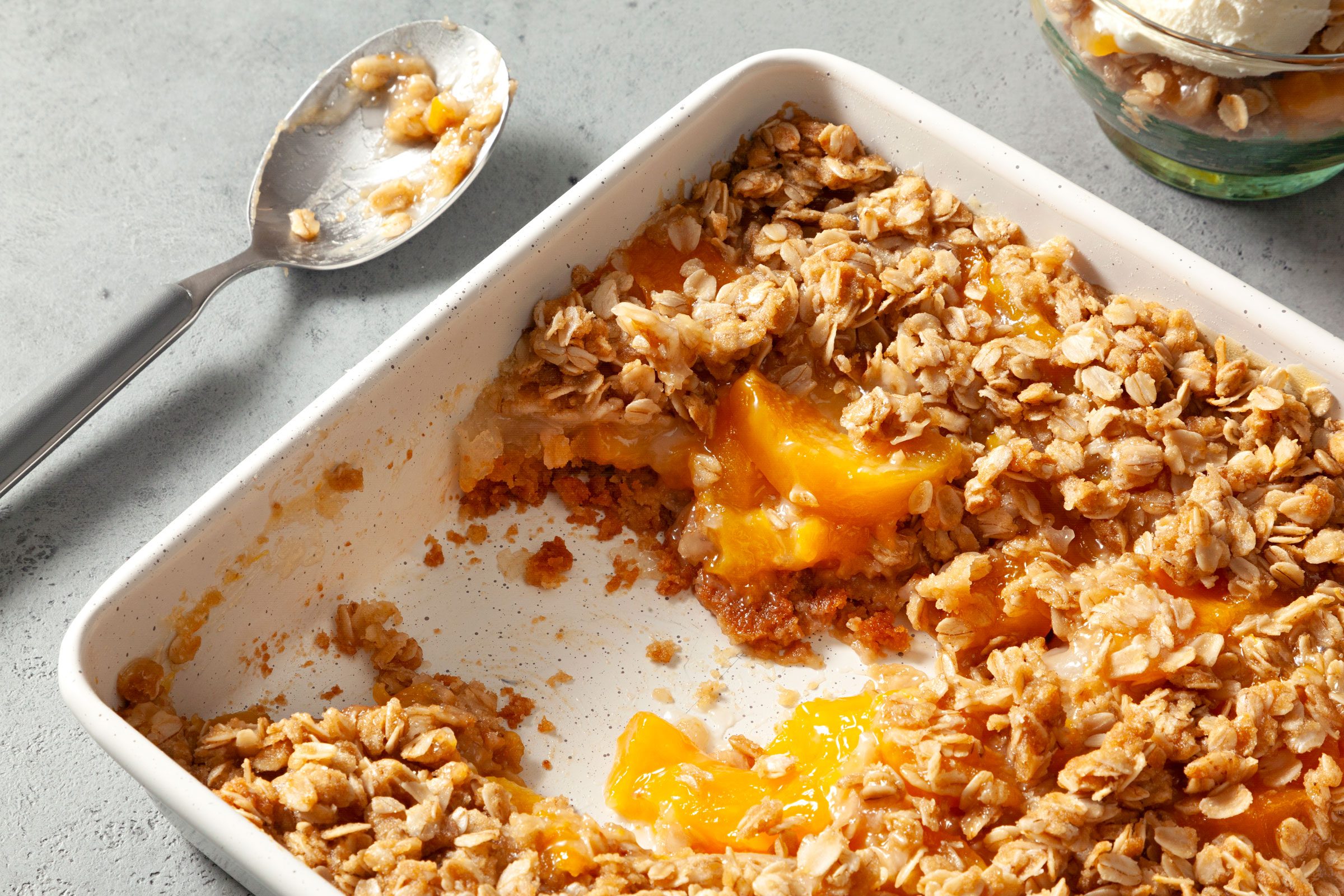 close up of Peach Crisp With Canned Peaches in a baking dish with a section already scooped out