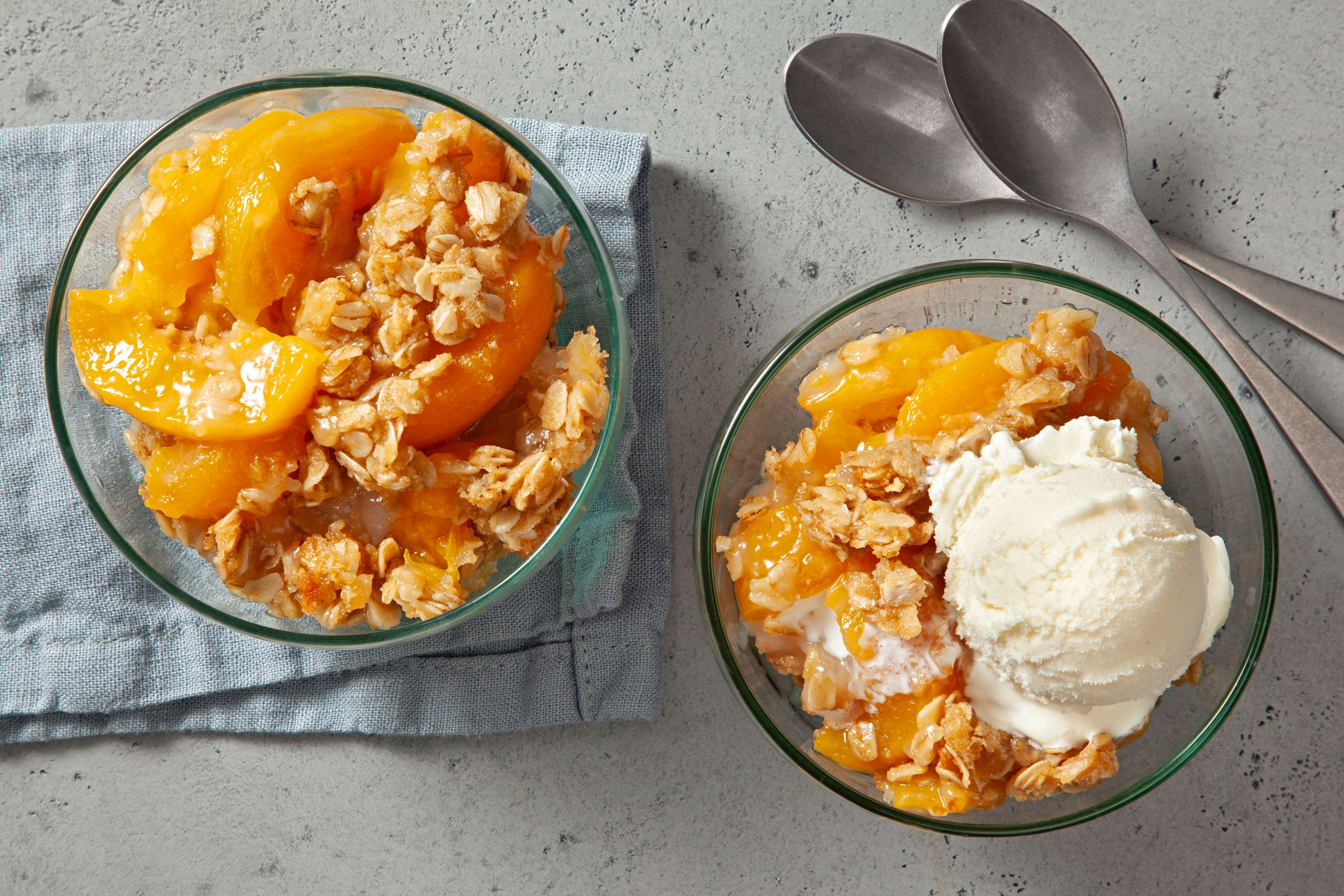 Peach Crisp With Canned Peaches served in two small bowls, one is topped with vanilla ice cream