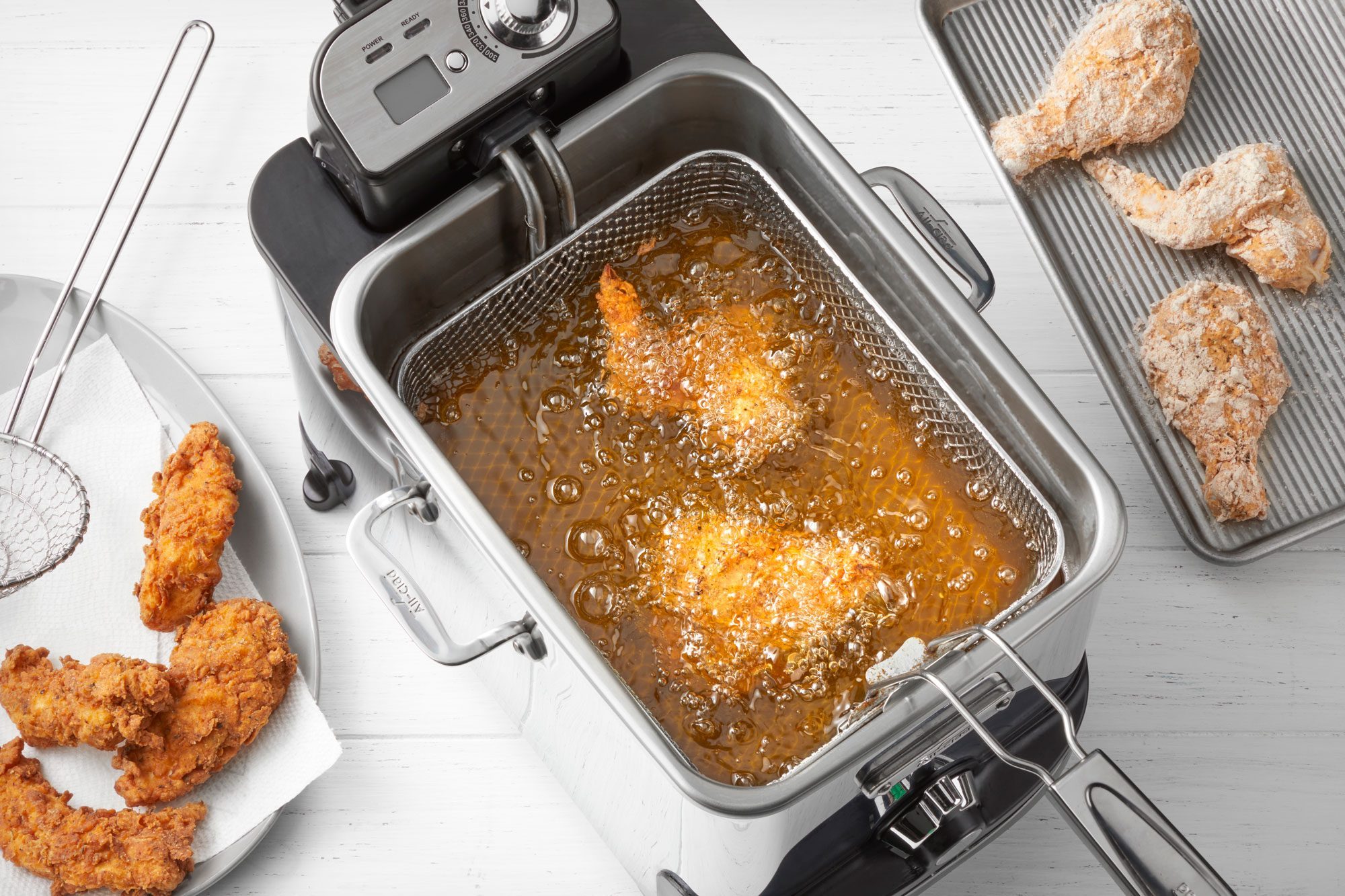 overhead shot of frying chicken in a deep fryer; wooden background;