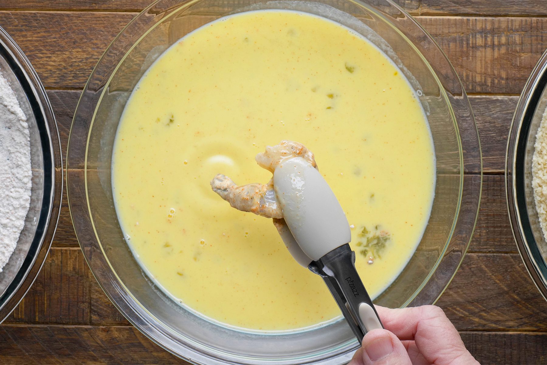 a person dipping shrimp in egg mixture