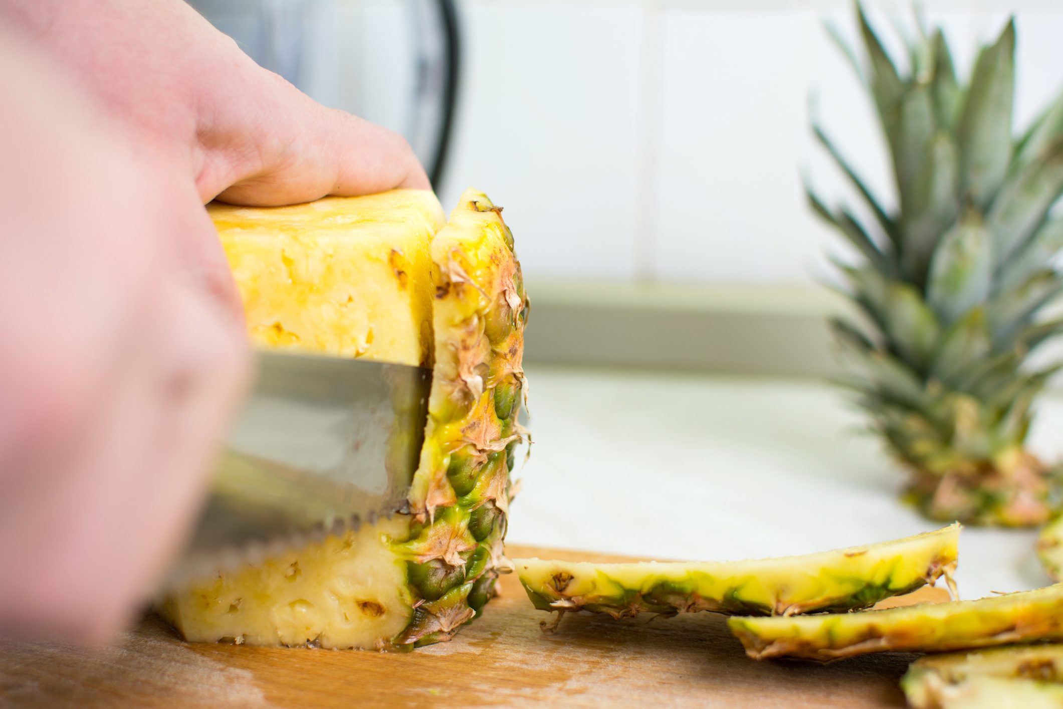 Male hands peeling fresh pineapple skin