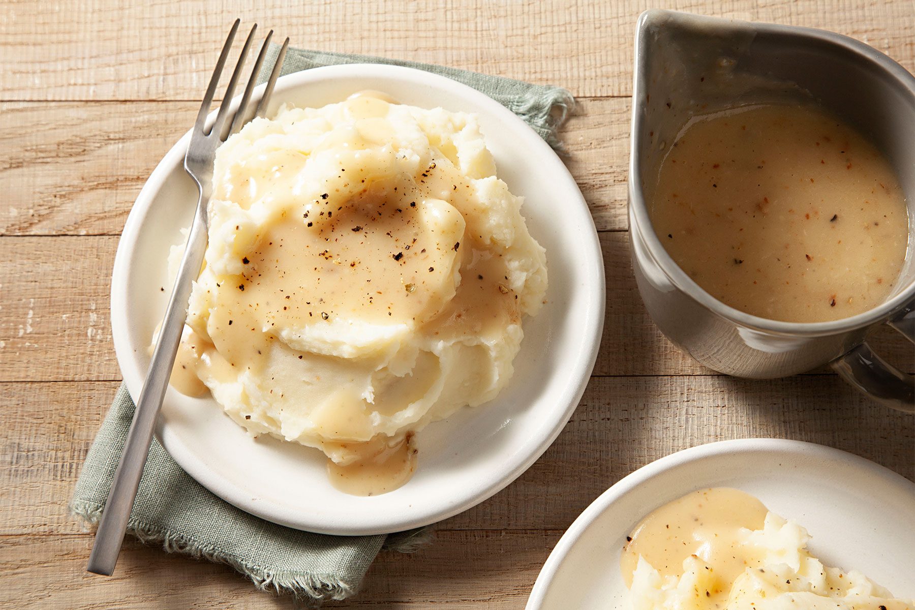 Overhead shot of Ham Gravy; poured over ham mashed potatoes; served on a small plates; with fork; napkin; wooden background;