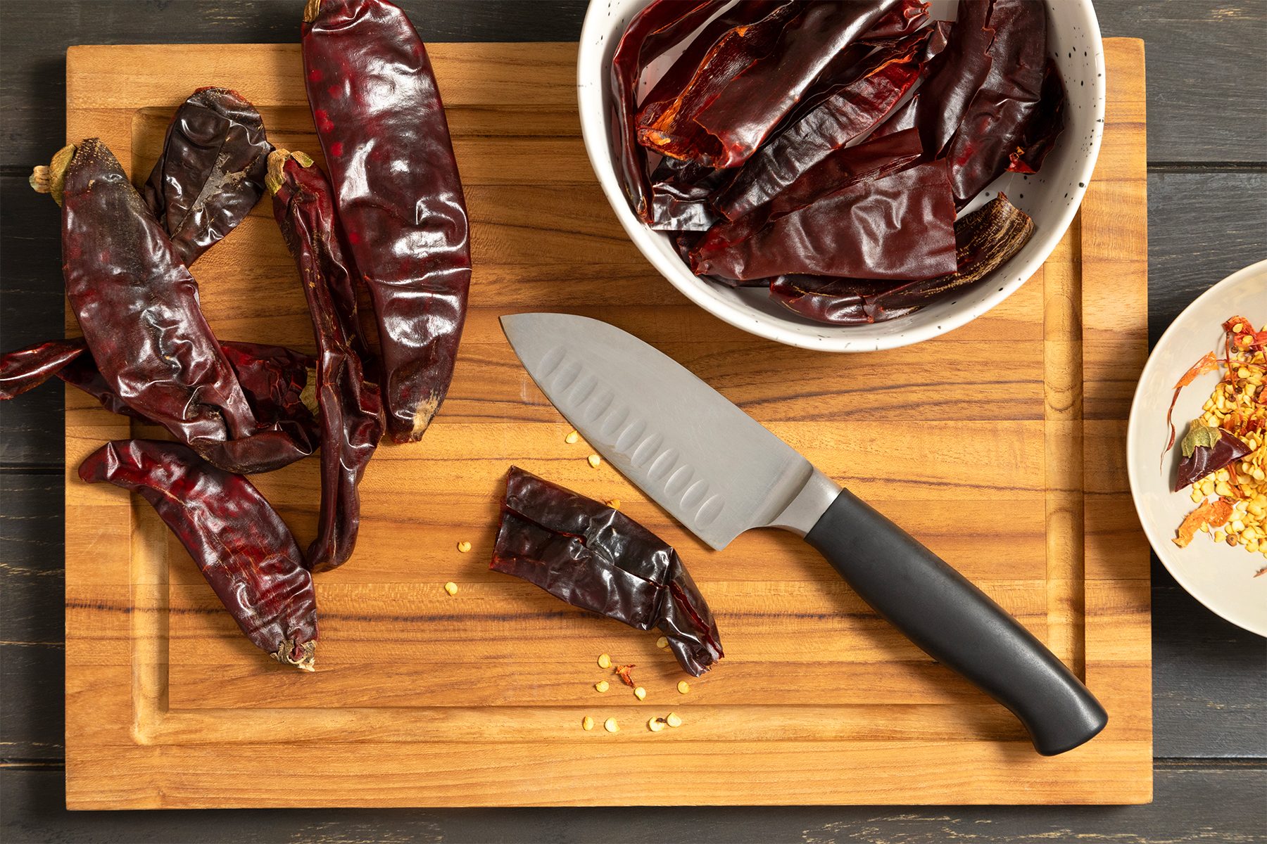 a bowl of red peppers & Knife On Cutting Board