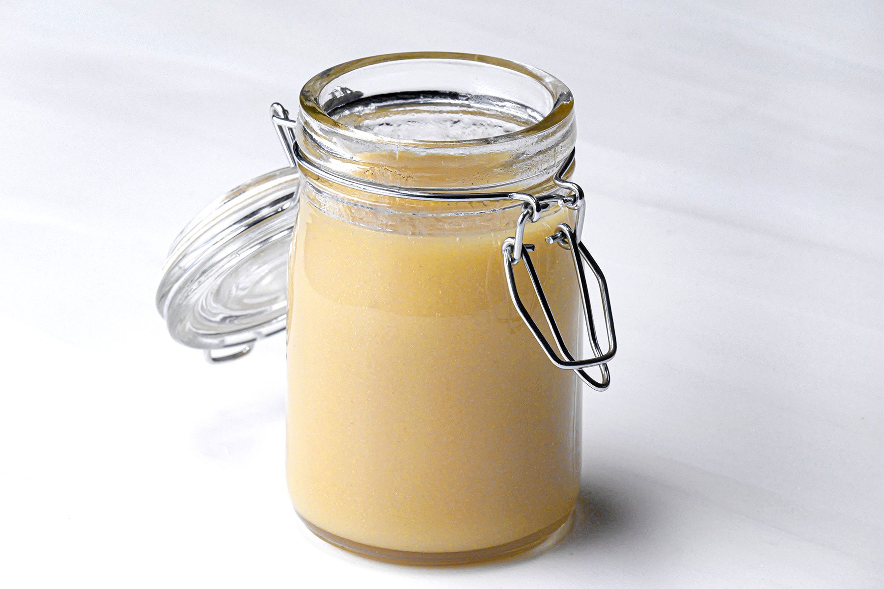 3/4 angle view shot of Fast Honey-Mustard Salad Dressing; stored in glass jar; white background;