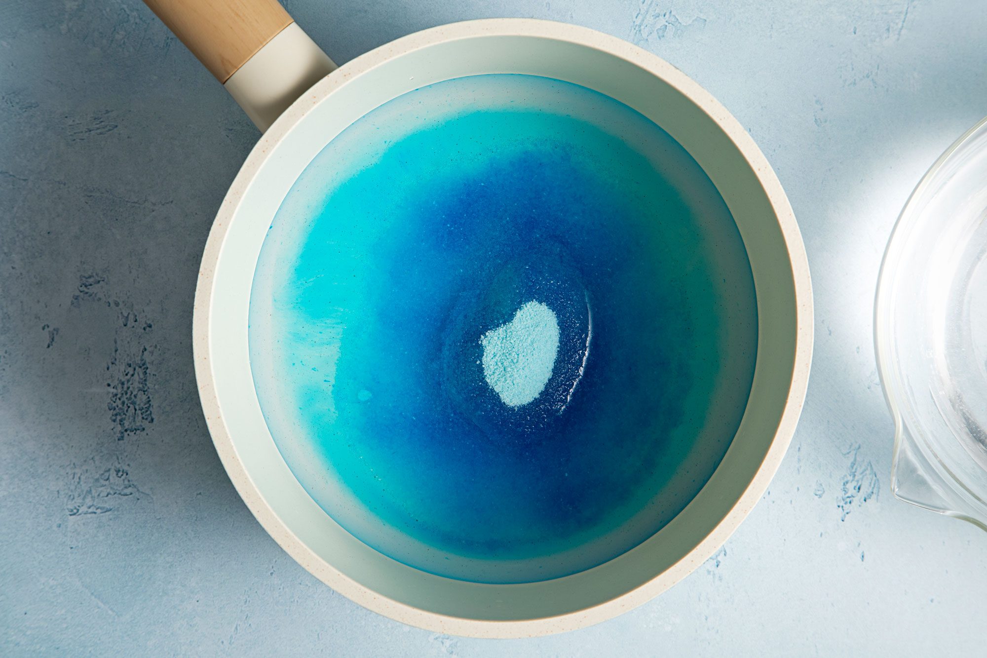 overhead shot of berry blue gelatin with water in a sauce pan