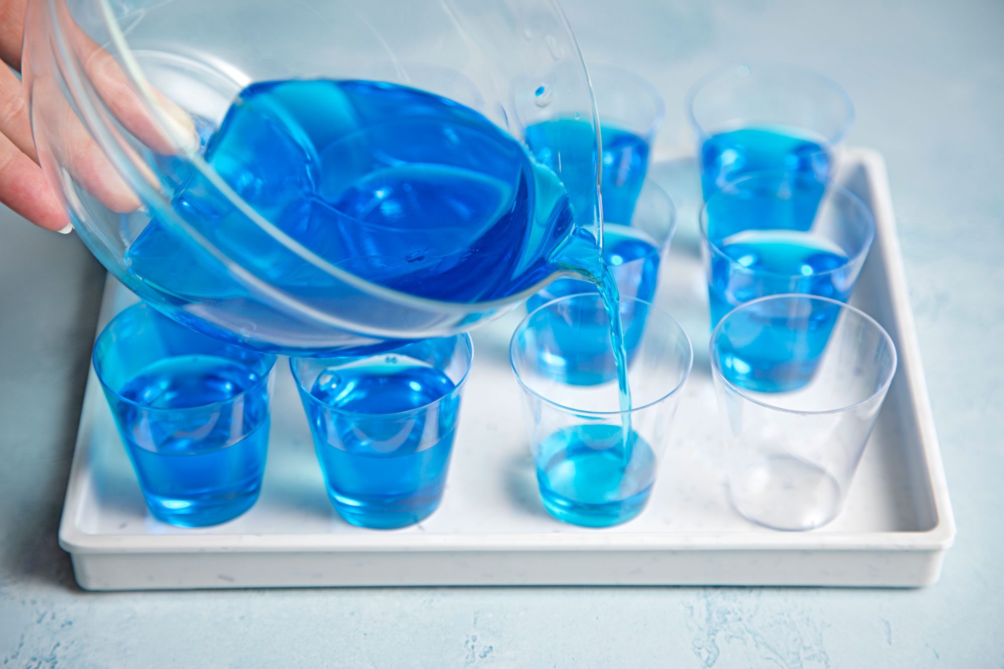 wide shot of berry blue mix poured into shot glasses