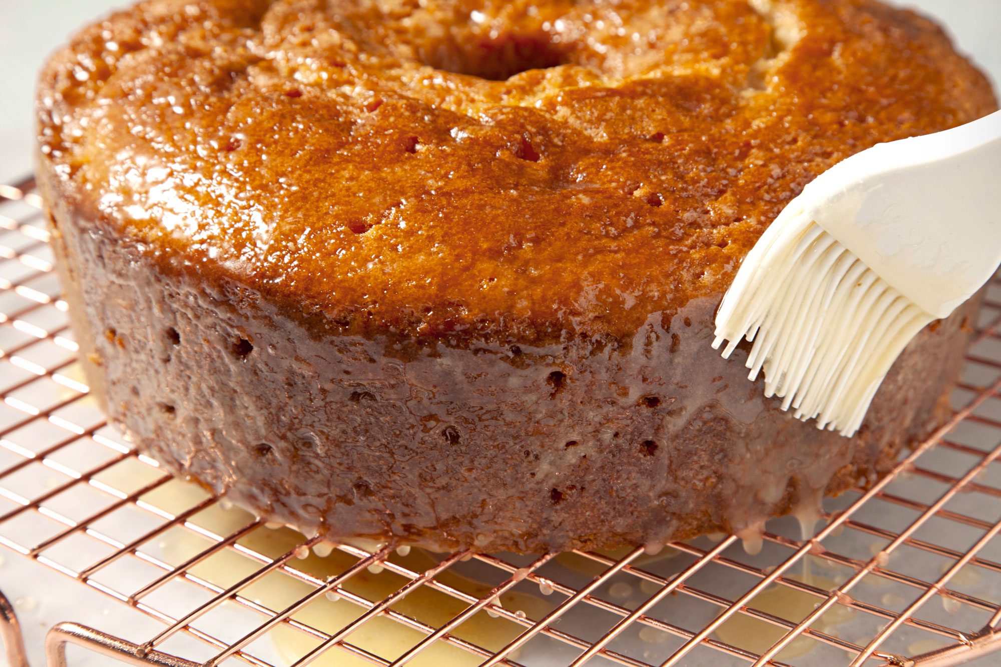 brushing butter on Kentucky Butter Cake on a wire rack