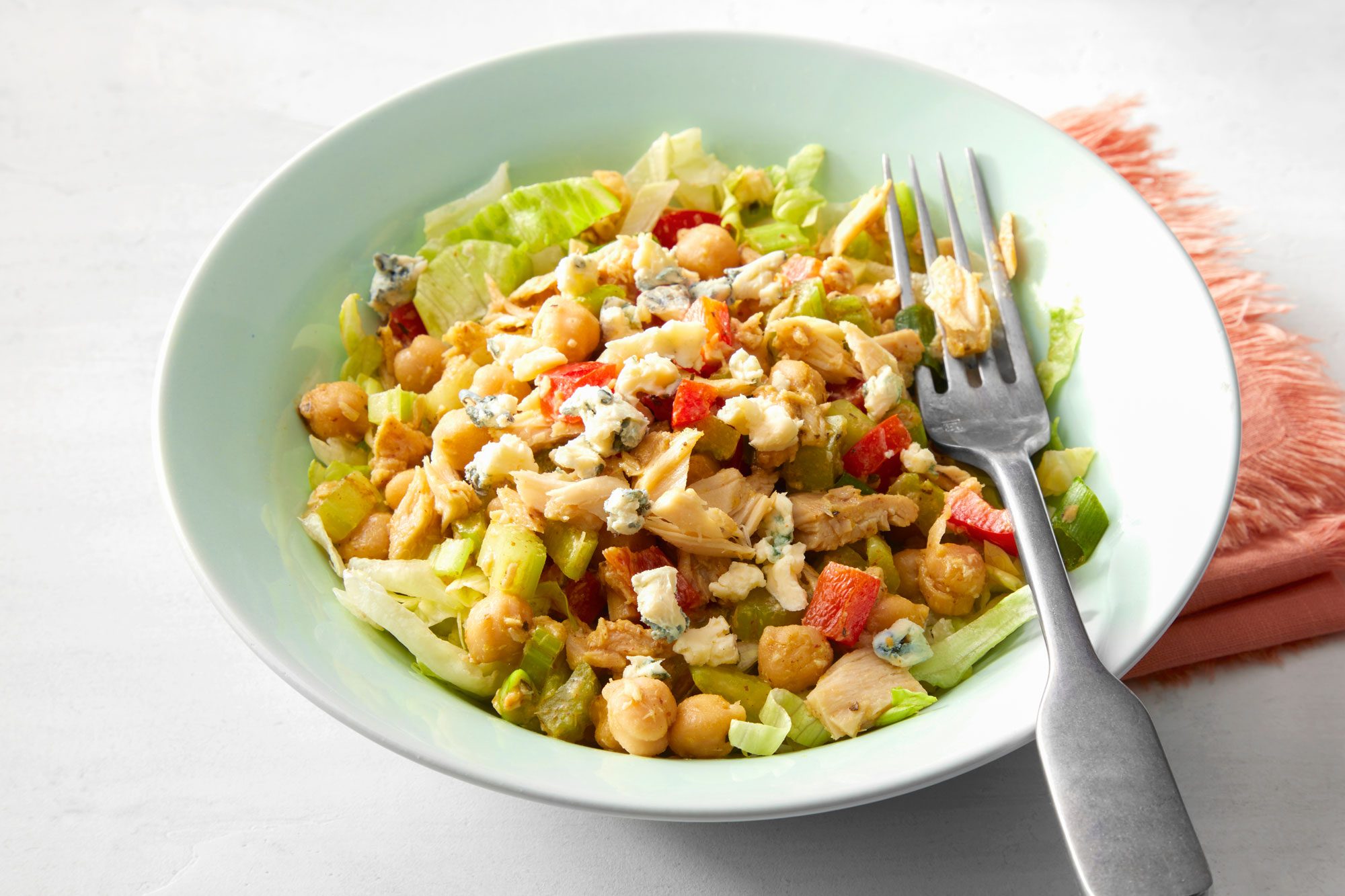 Vibrant bowl of Mediterranean Tuna Salad with chicken, peppers, and cheese with fork