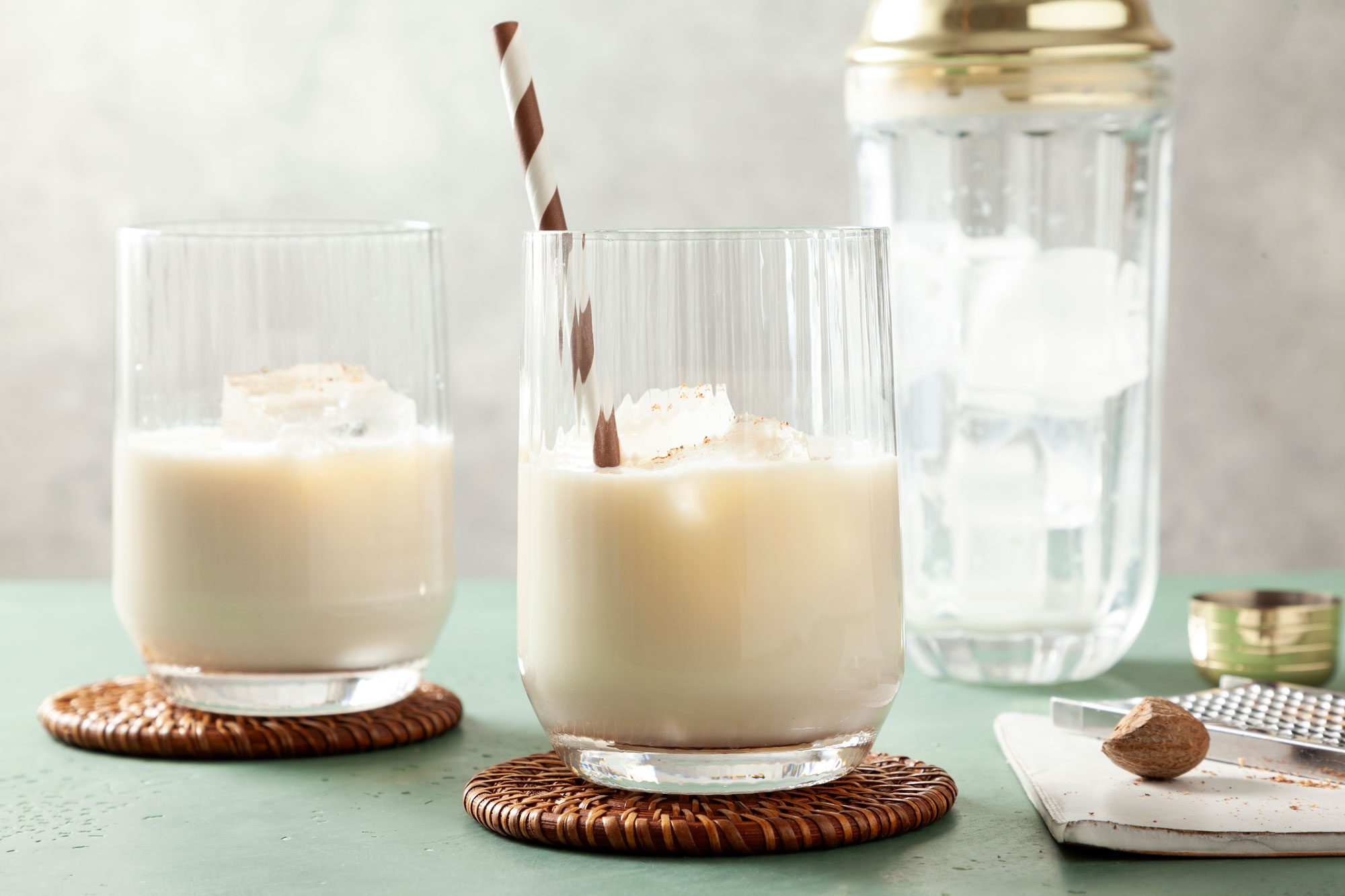 Two delicious Milk Punch glasses of with ice and straws sprinkled with nutmeg