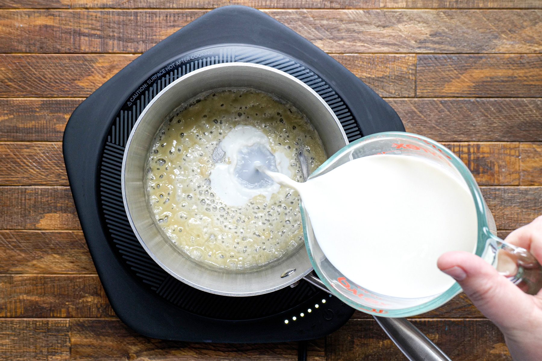 A person pouring milk into Saucepan