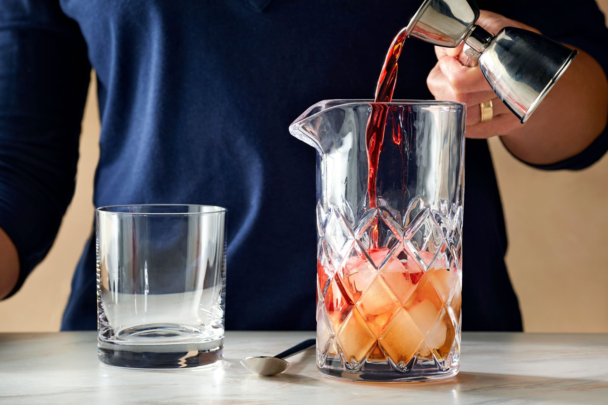 pouring campari in a mixing glass; marble surface;