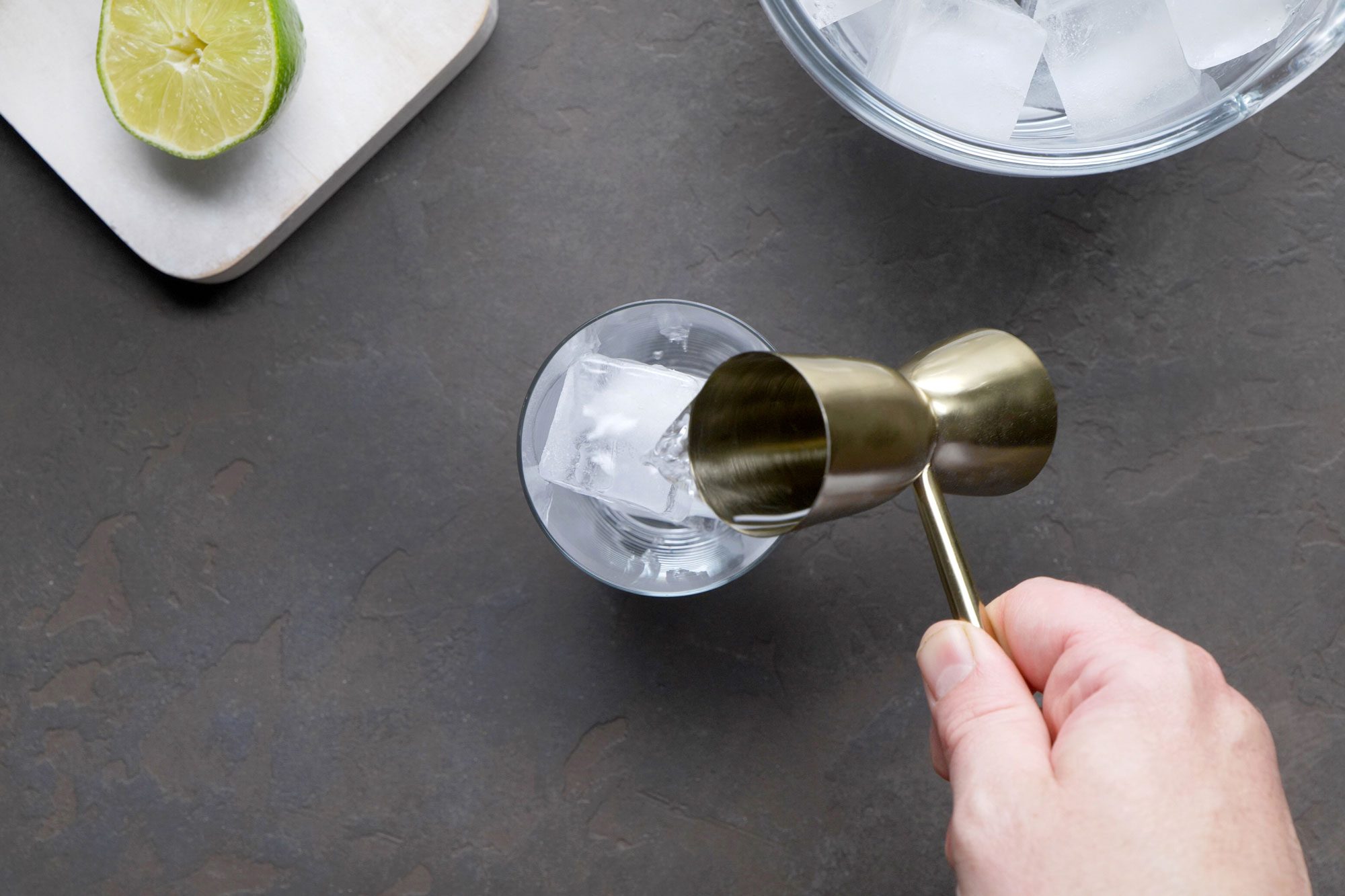 Overhead shot of add tequila; chopping board; ice jar; black texture background;