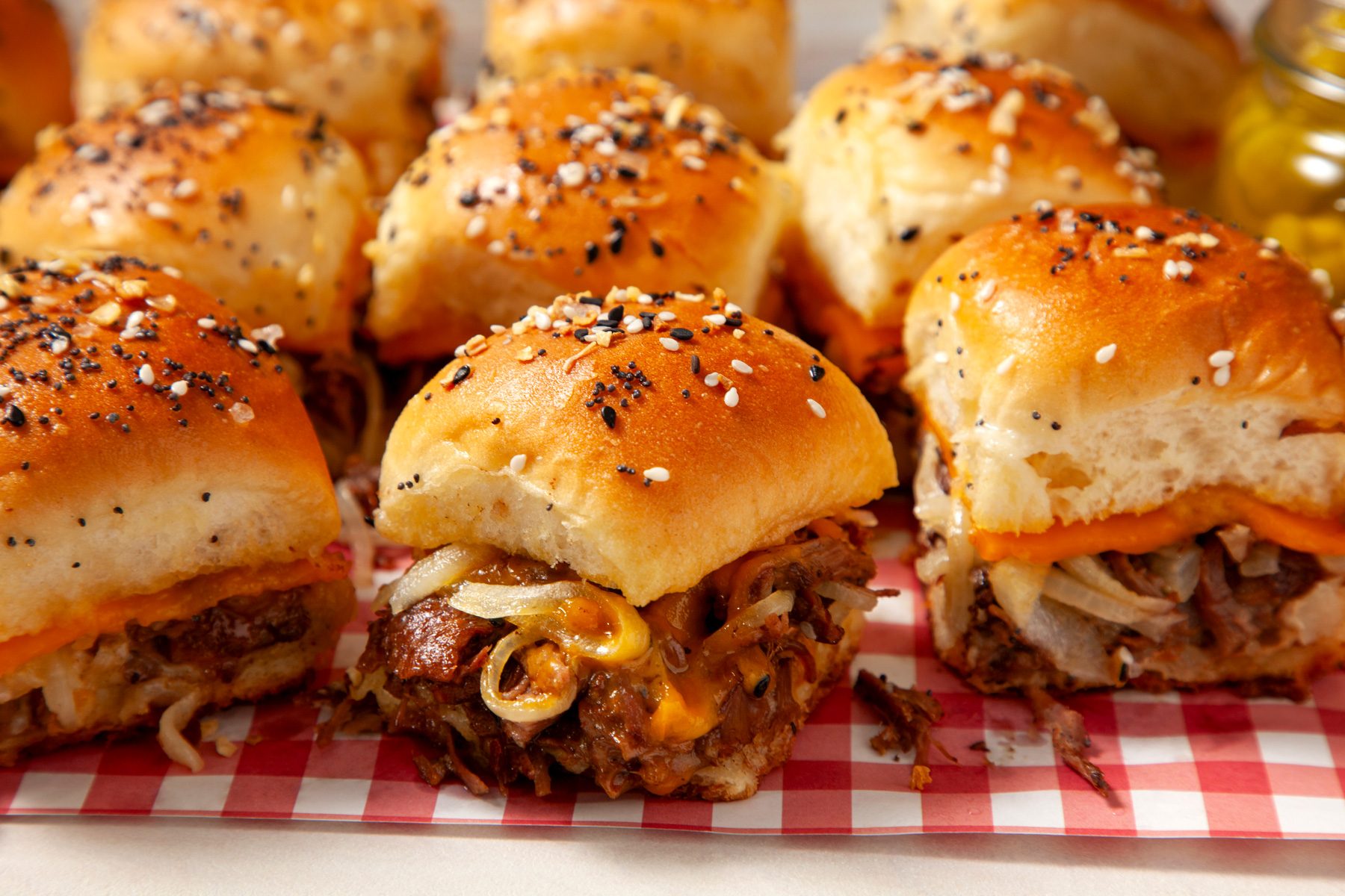 A group of roast beef sliders on a red and white checkered surface