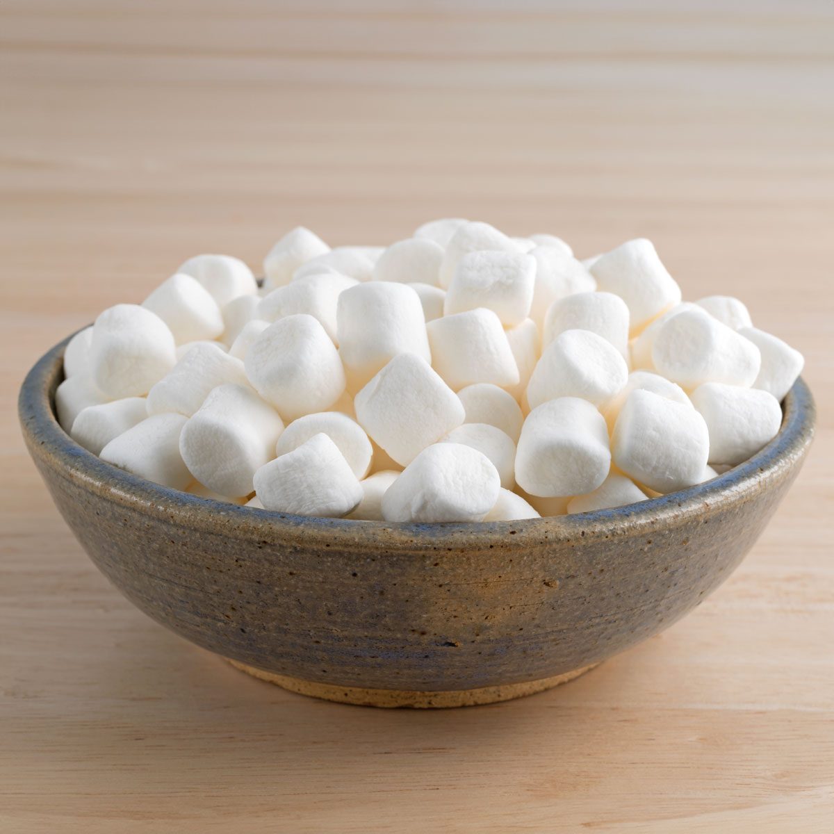 Small Bite Size Marshmallows Filling An Old Stoneware Bowl On A Wood Table
