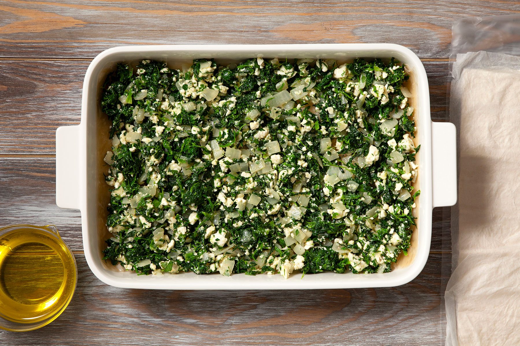 Spreading spinach and onion mixture on brushed dough