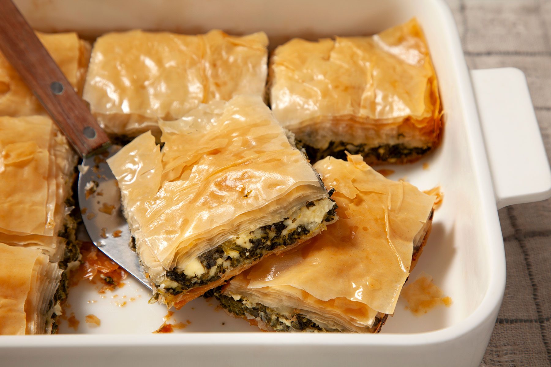 Picking up piece of baked Spanakopita 