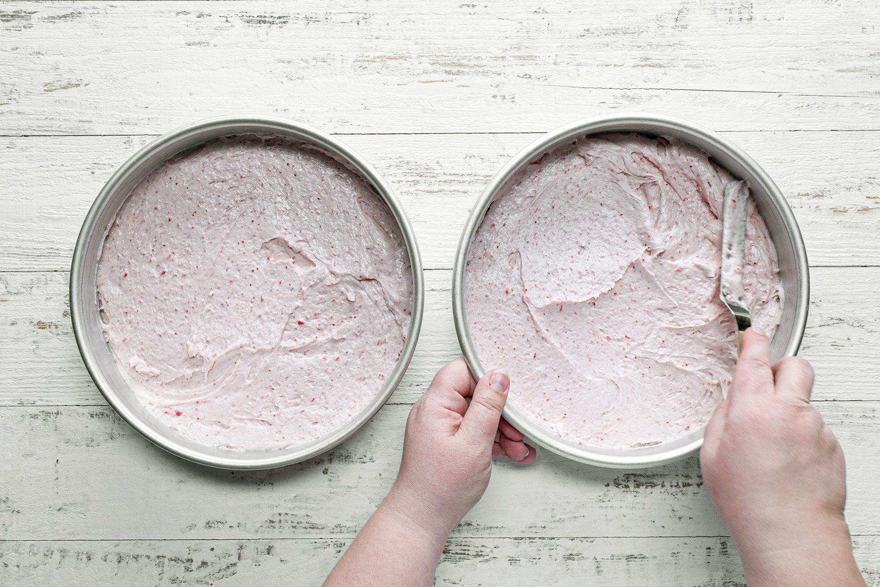 Spreading cake batter in two cake pans 