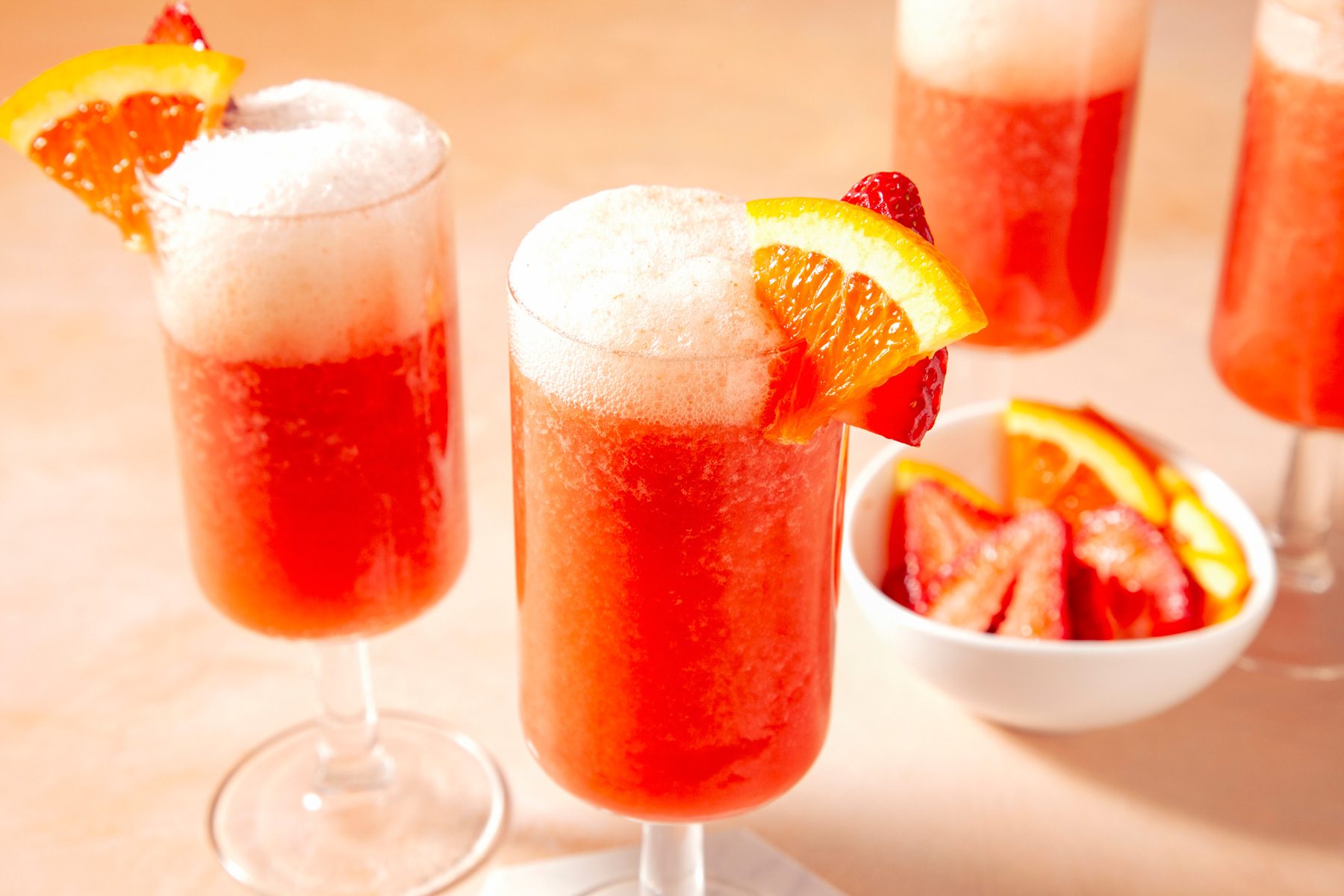 Two glass of strawberry mimosas garnished with strawberry and orange slice