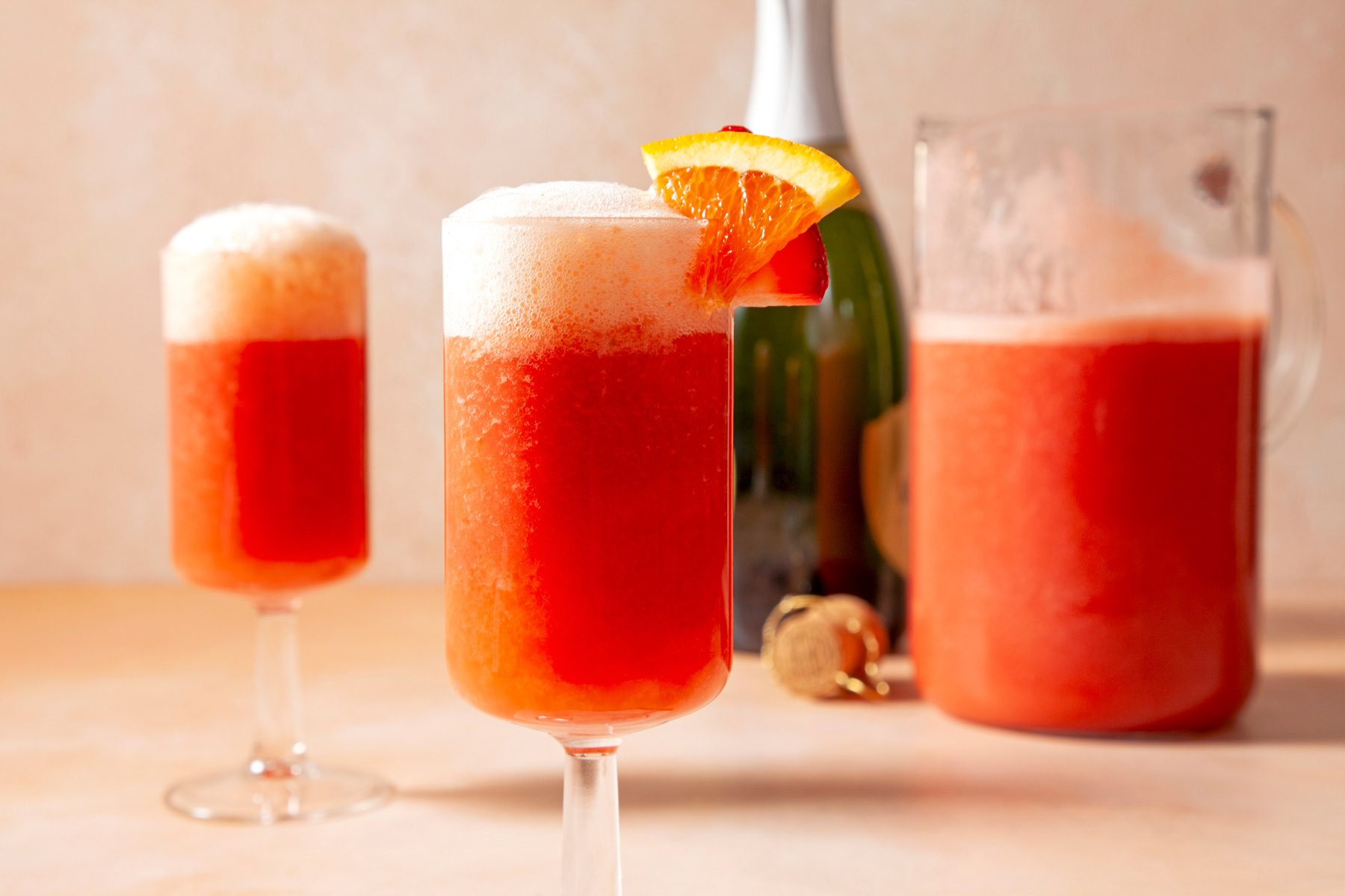 Two glass of strawberry mimosas garnished with strawberry and orange slice