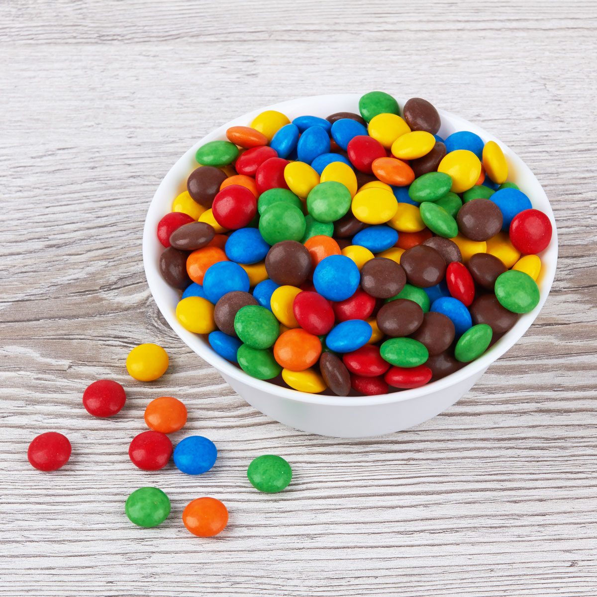 A Bowl Of Colorful Chocolate Candies On Wooden Background