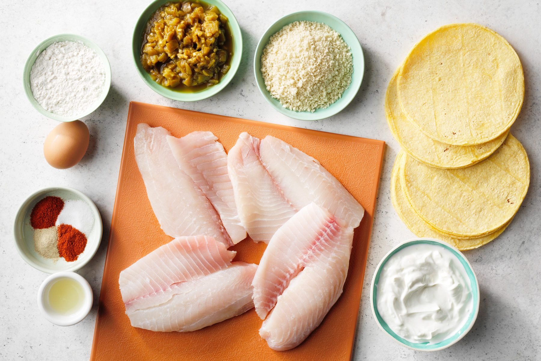Tilapia fish, flour, bread crumbs, and other ingredients prepared for Air-Fryer Fish Tacos