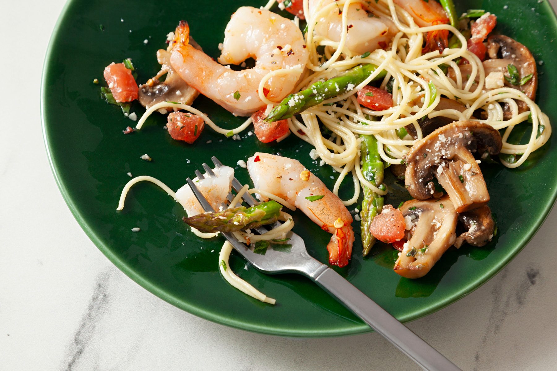 A green plate of Shrimp Asparagus Pasta with a fork