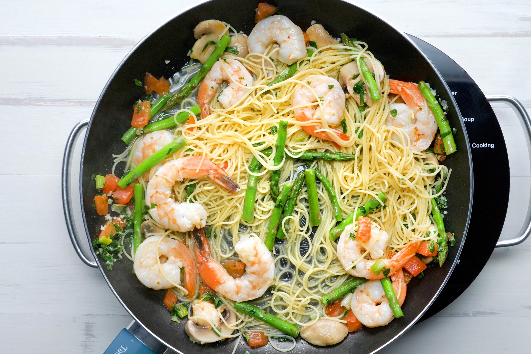 Noodles, Shrimps and vegetables are cooking in a small skillet