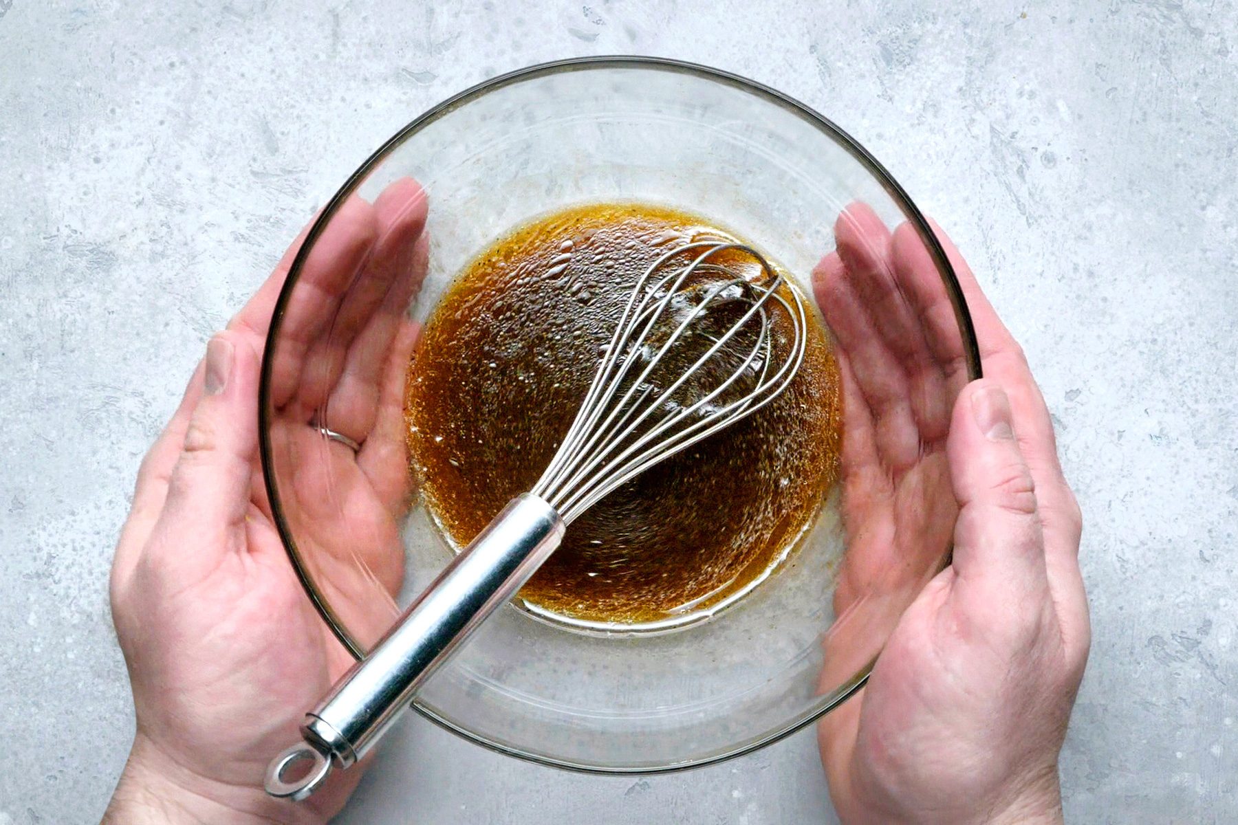 A small bowl of liquid mixture with a whisk resting on top