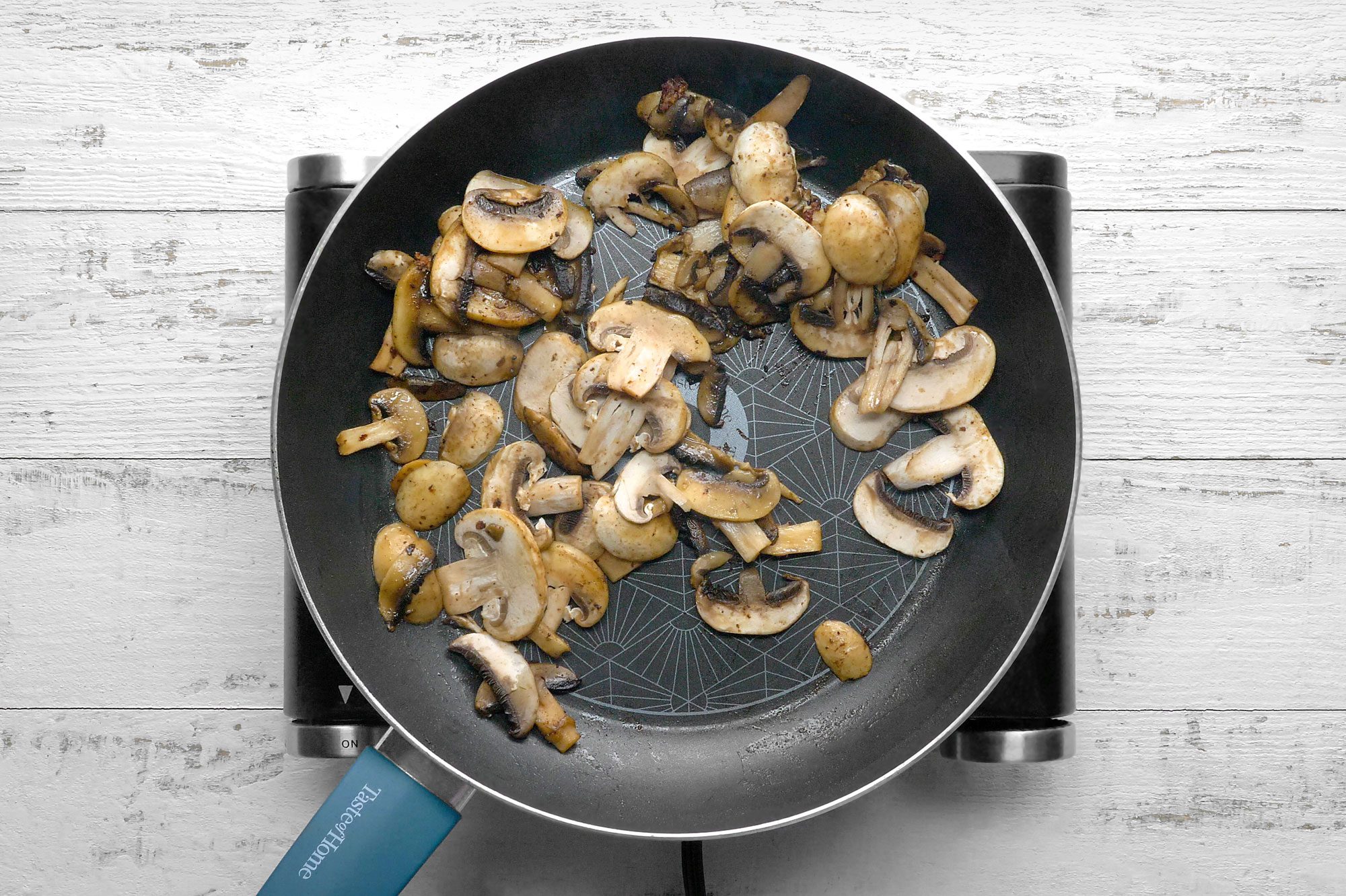 overhead shot; white wooden background; Add mushrooms to skillet;