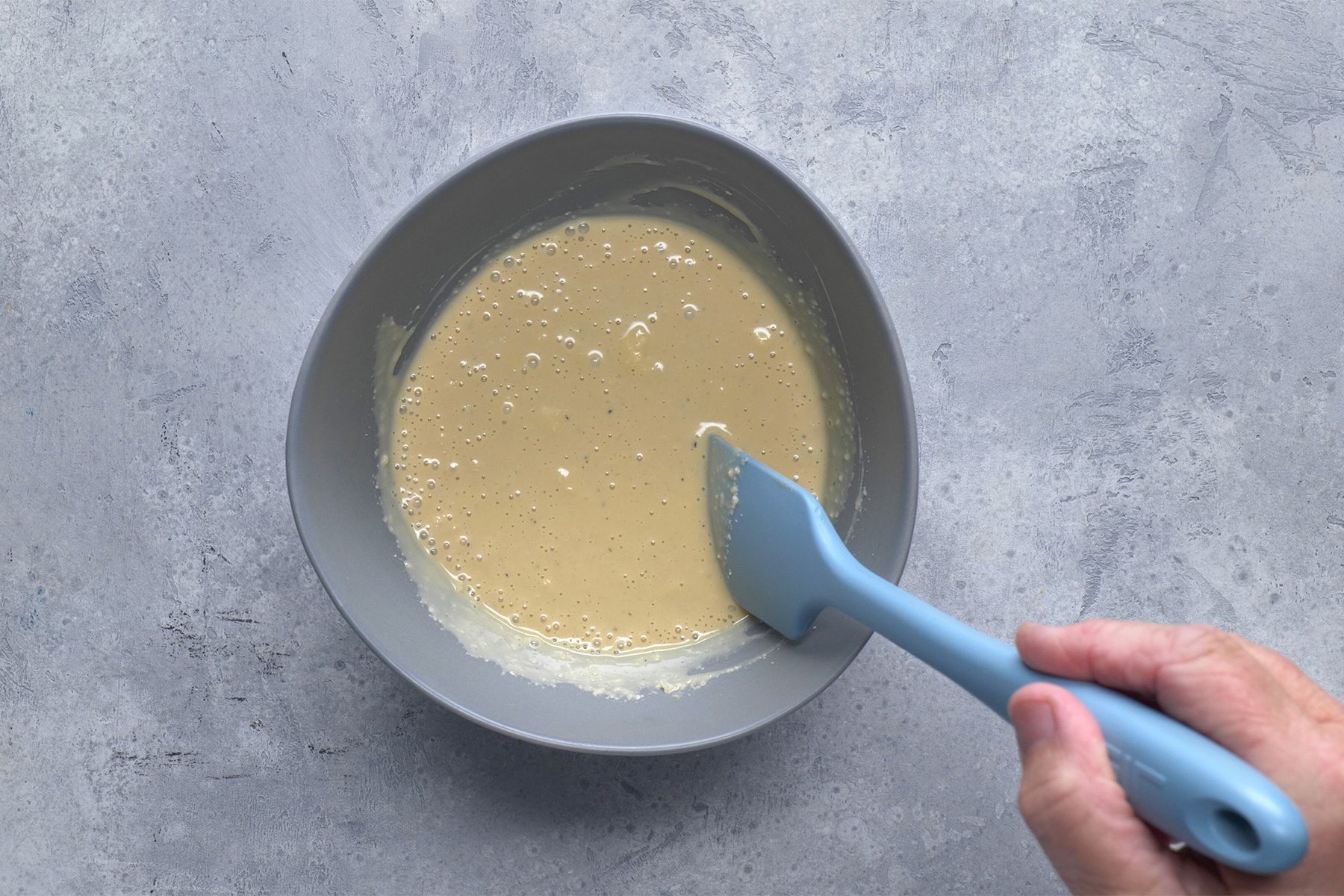 Overhead shot of bowl; stir in Parmesan cheese; chill until serving; spatula; grey background