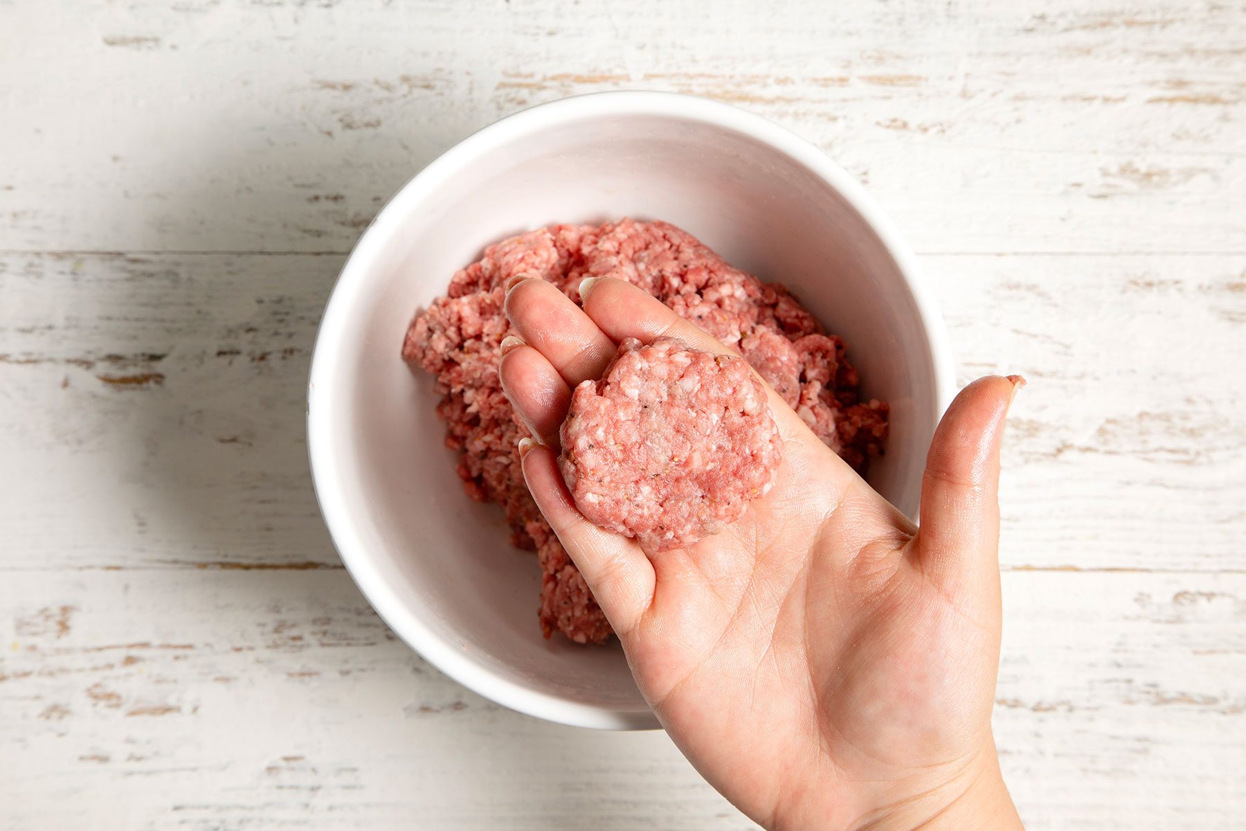 overhead shot; white textured background; shaped mixture into thick patty from a large bowl;