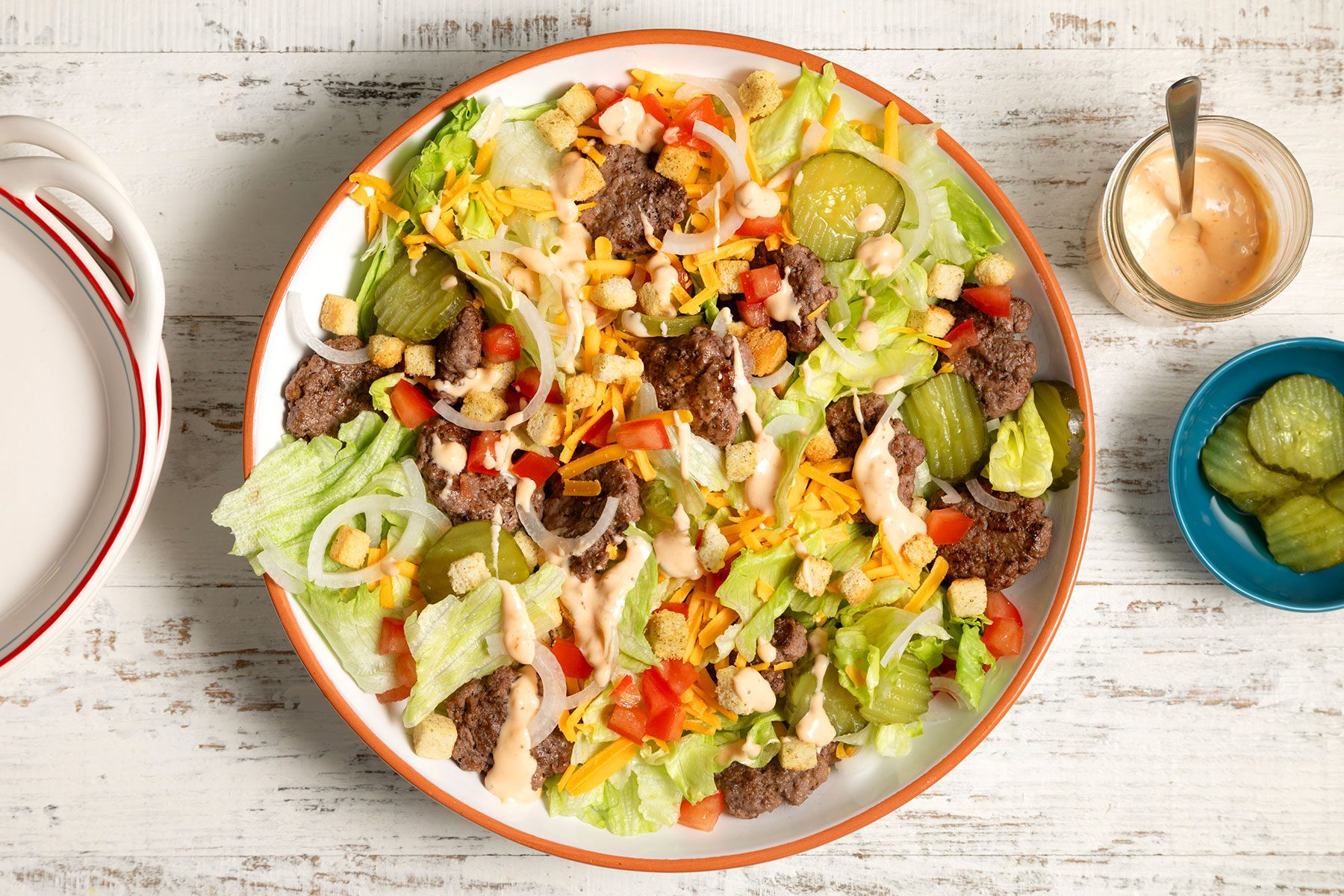 overhead shot; white textured background; Deluxe Cheeseburger Salad in a large bowl;