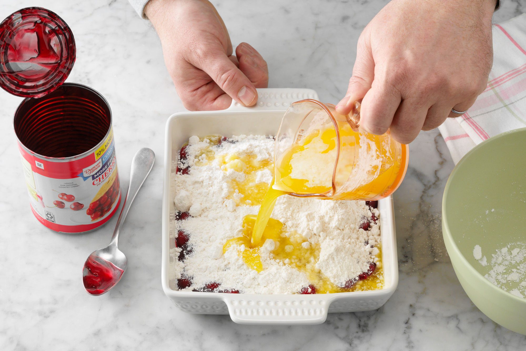 melted butter and extract being poured over the cake in baking dish