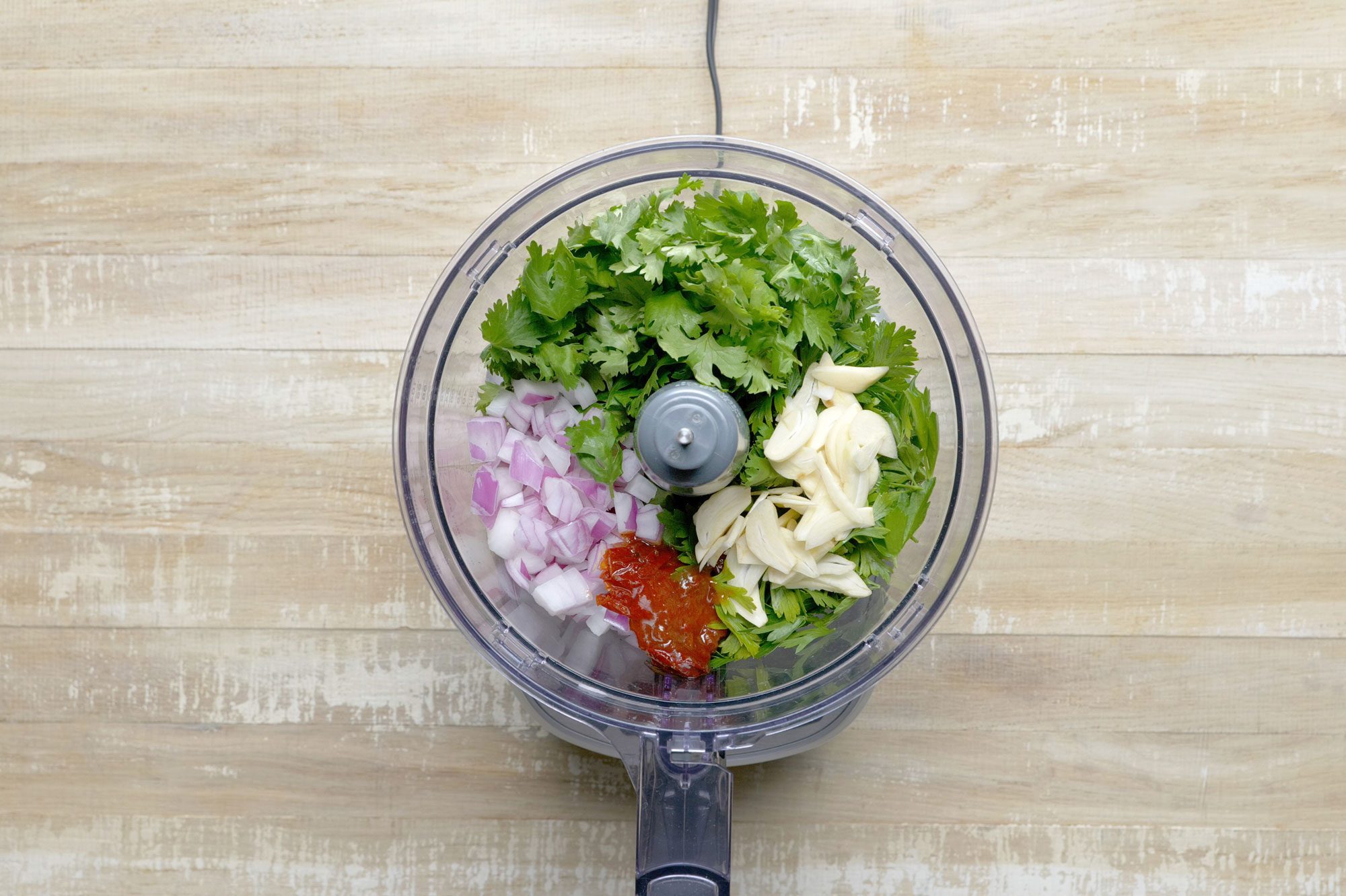 Place the parsley, cilantro, red onion, chipotle peppers and garlic in a food processor