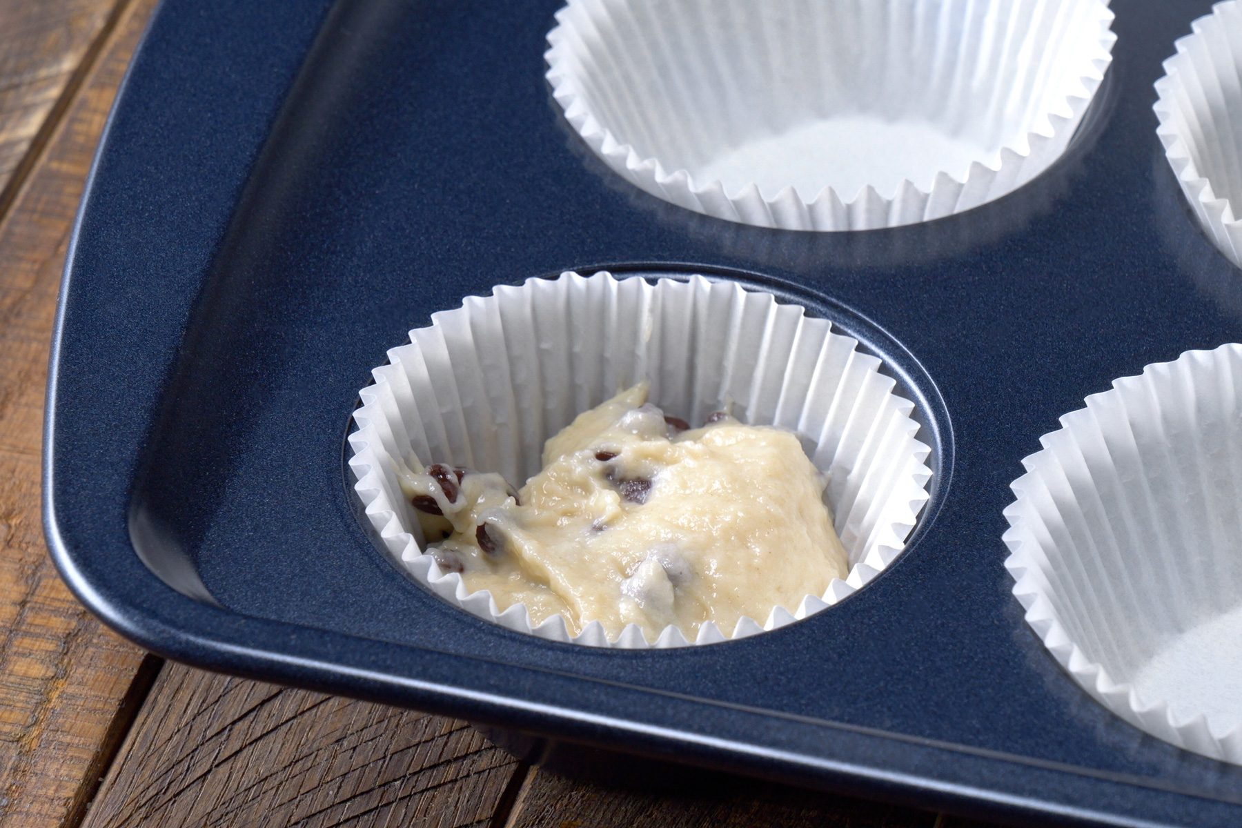 A tray filled with muffin cups containing Chocolate Chip Muffin batter.